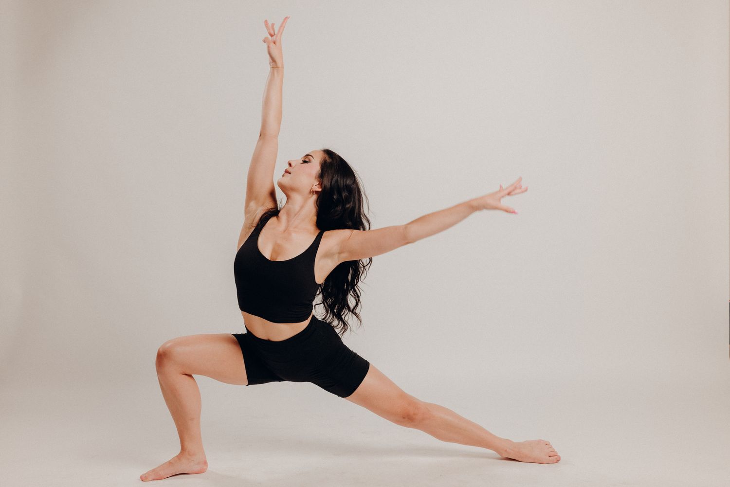 Dancer in black leotard performs graceful poses against white backdrop in artistic photo sequence.