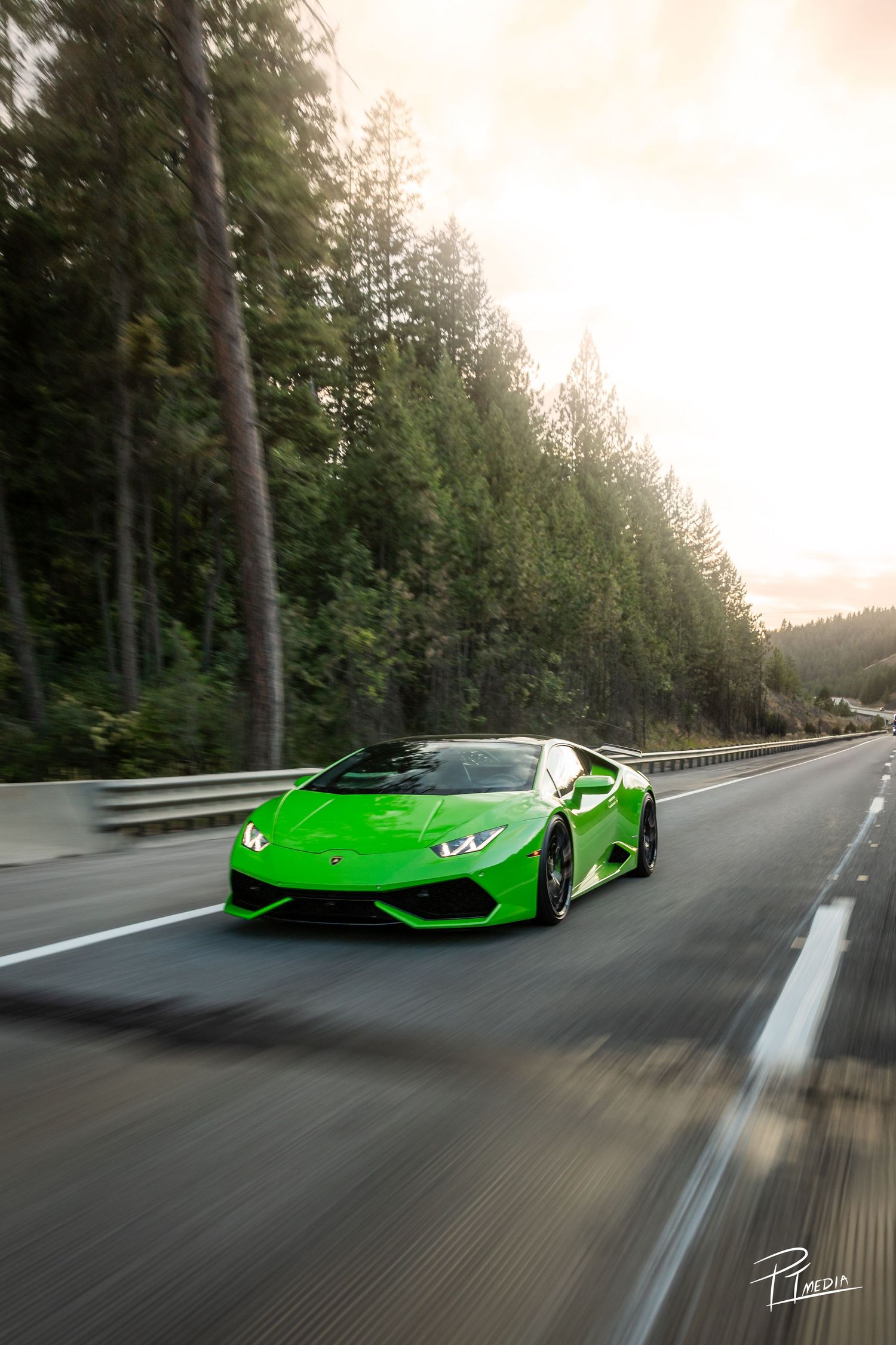 A bright green Lamborghini Huracan speeds along a forest-lined mountain road in a cinematic motion blur sequence.