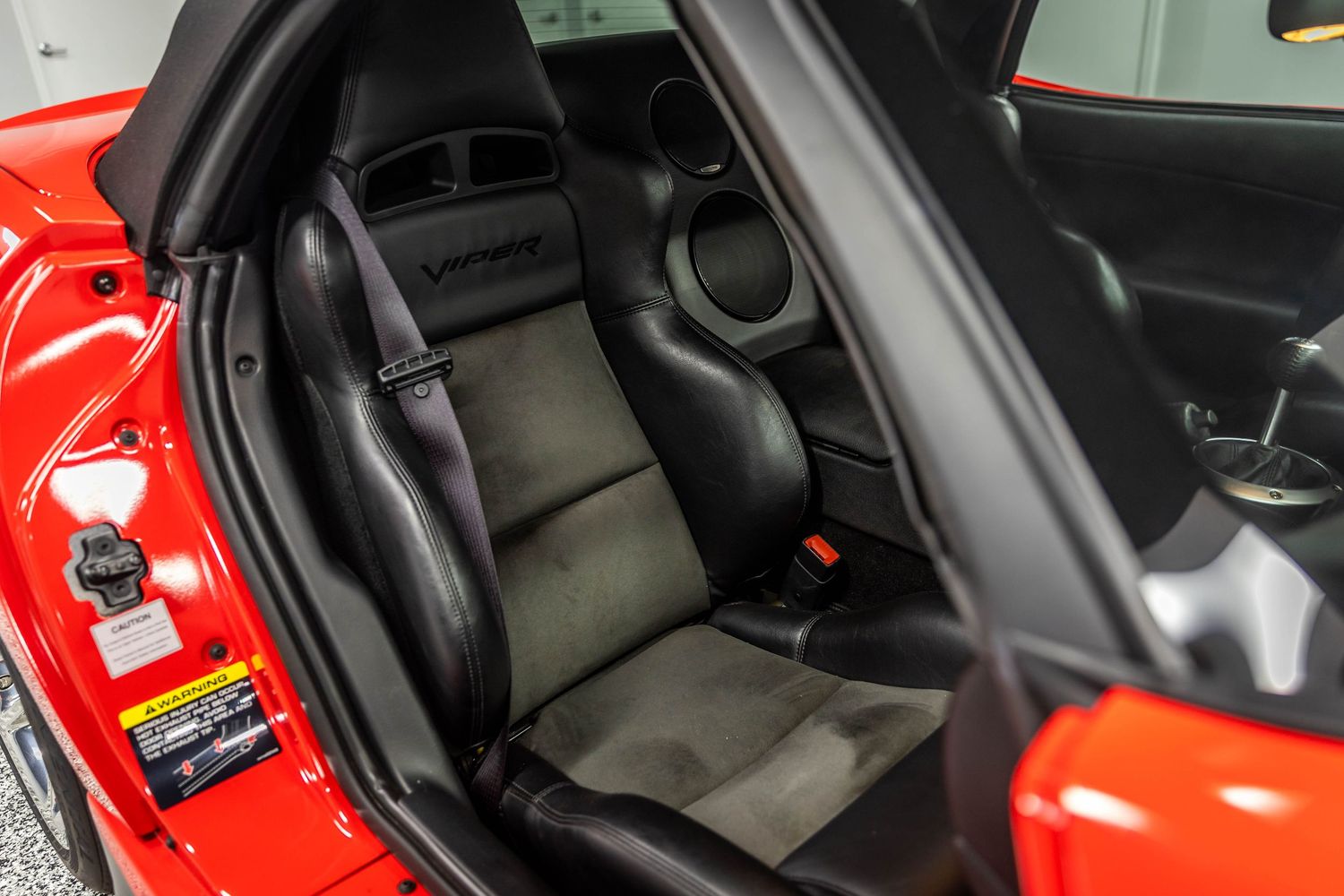 Interior view of a red sports car showing black leather seats and center console details.