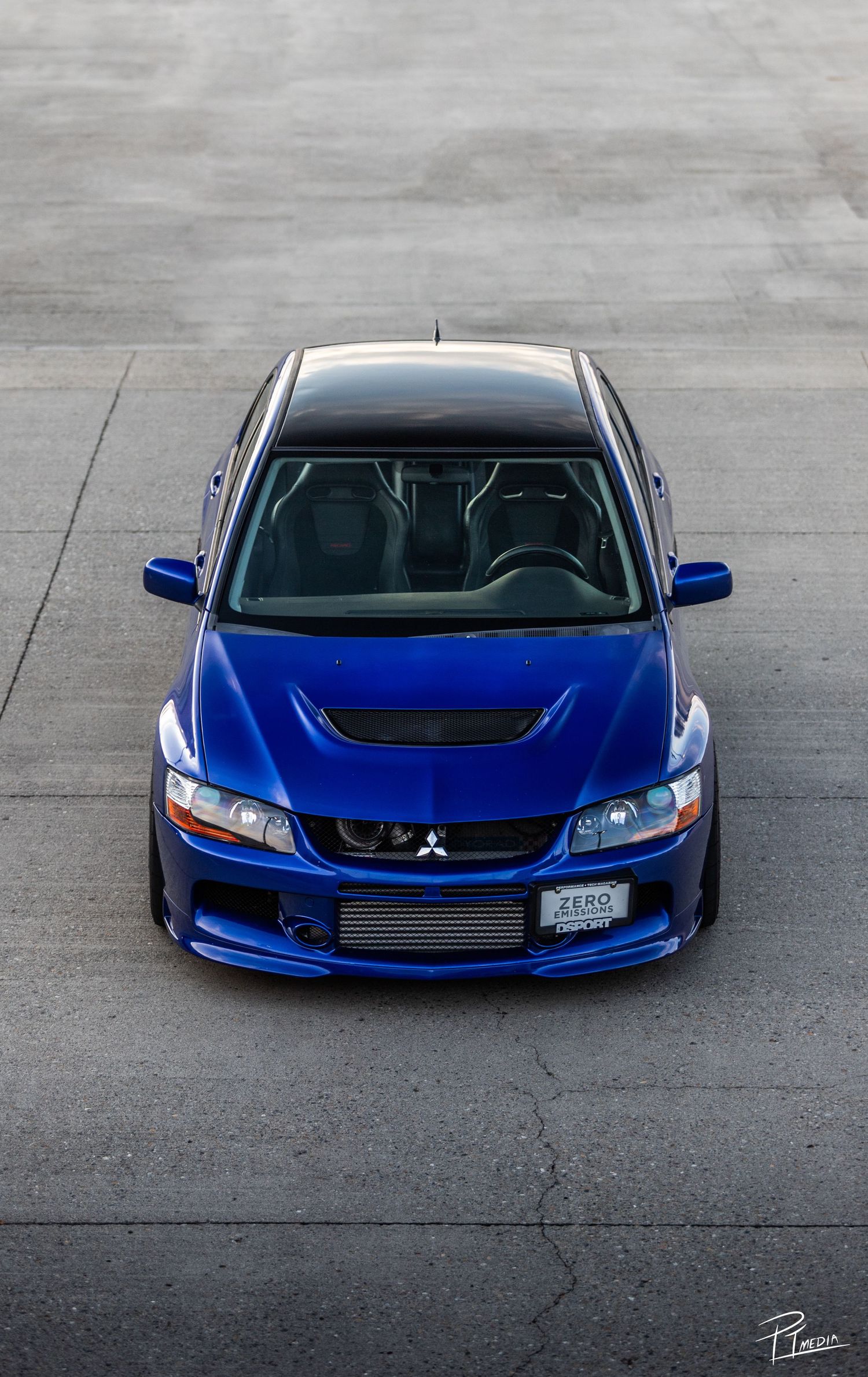 Blue Mitsubishi Evolution sports car shown from multiple front angles on concrete surface.