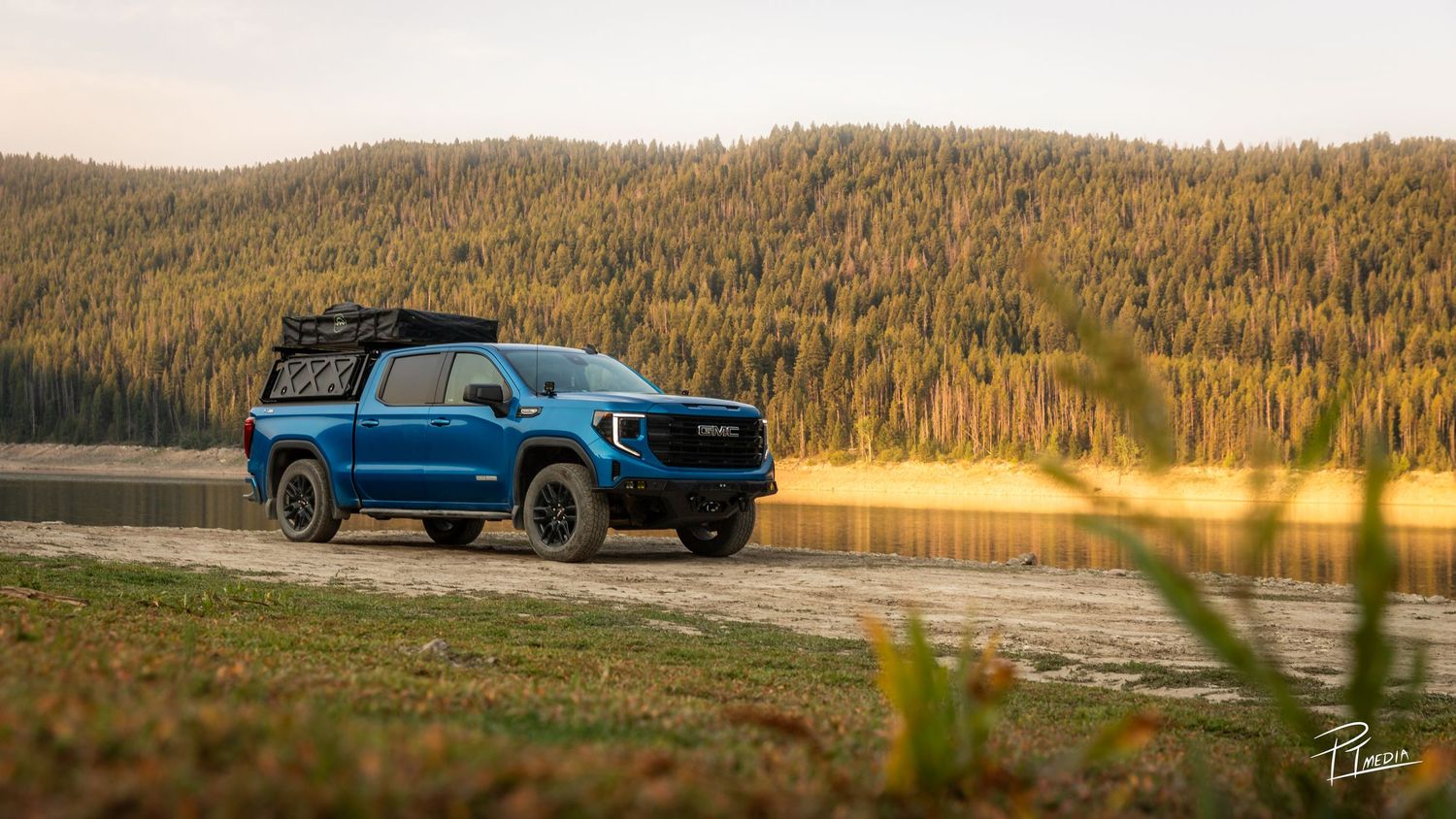 A panoramic view of a blue pickup truck parked on a scenic mountain road surrounded by golden autumn forest.