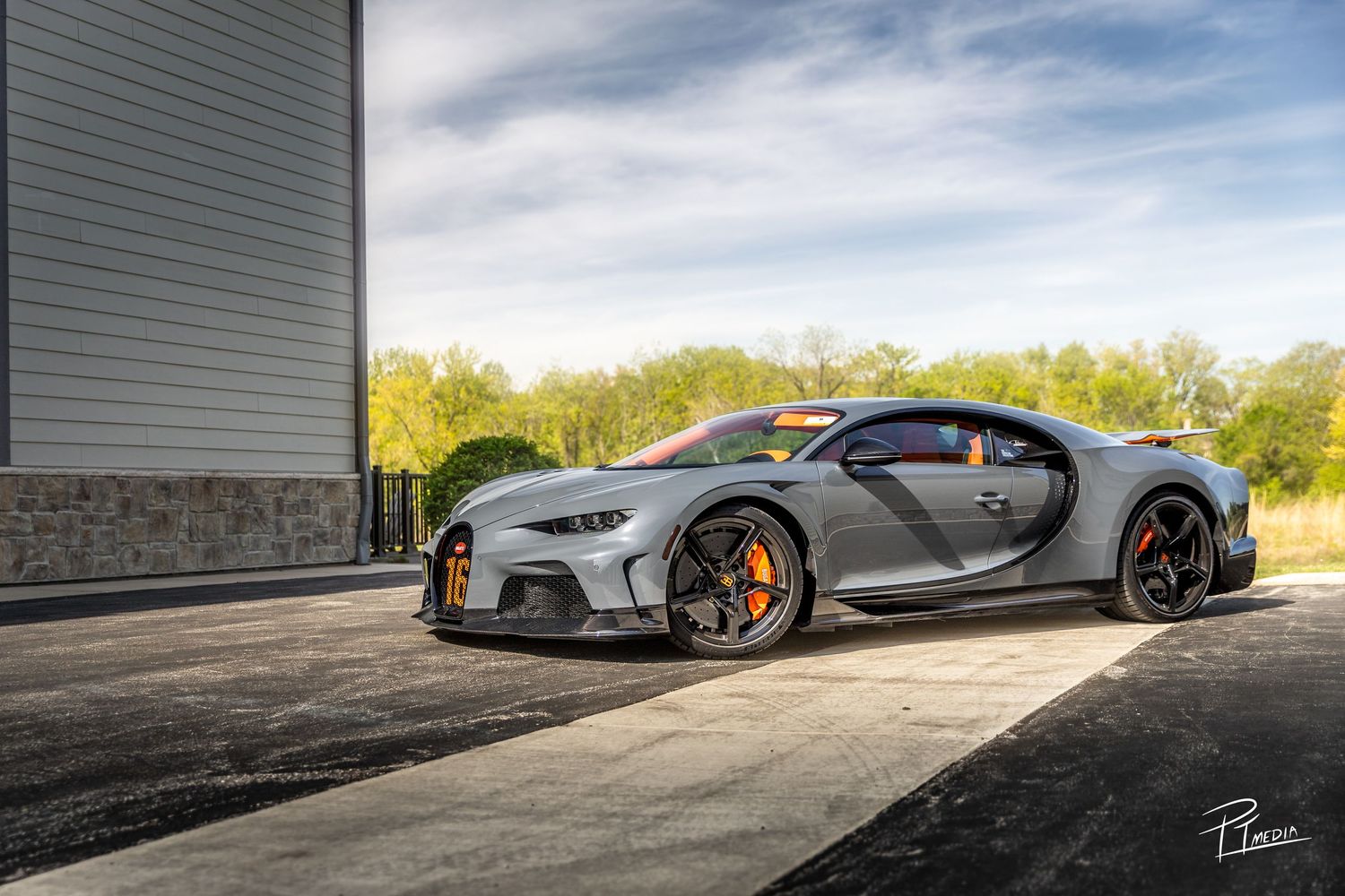 A sleek silver sports car sits in front of a garage door with dramatic lighting and shadows.