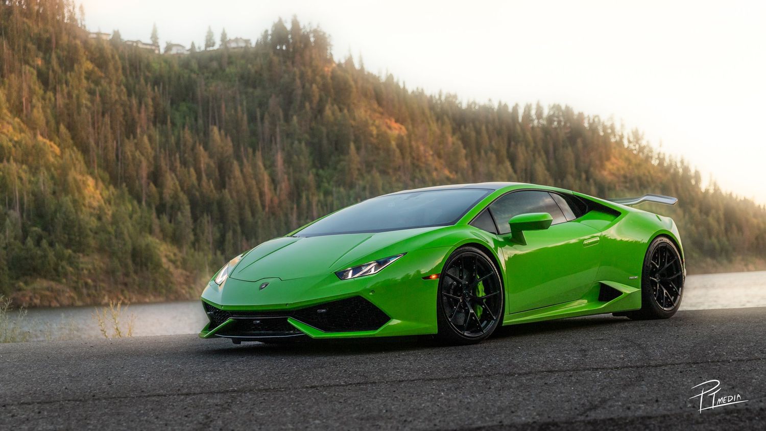 A bright green Lamborghini Huracan sports car photographed at sunset against a mountainous landscape.