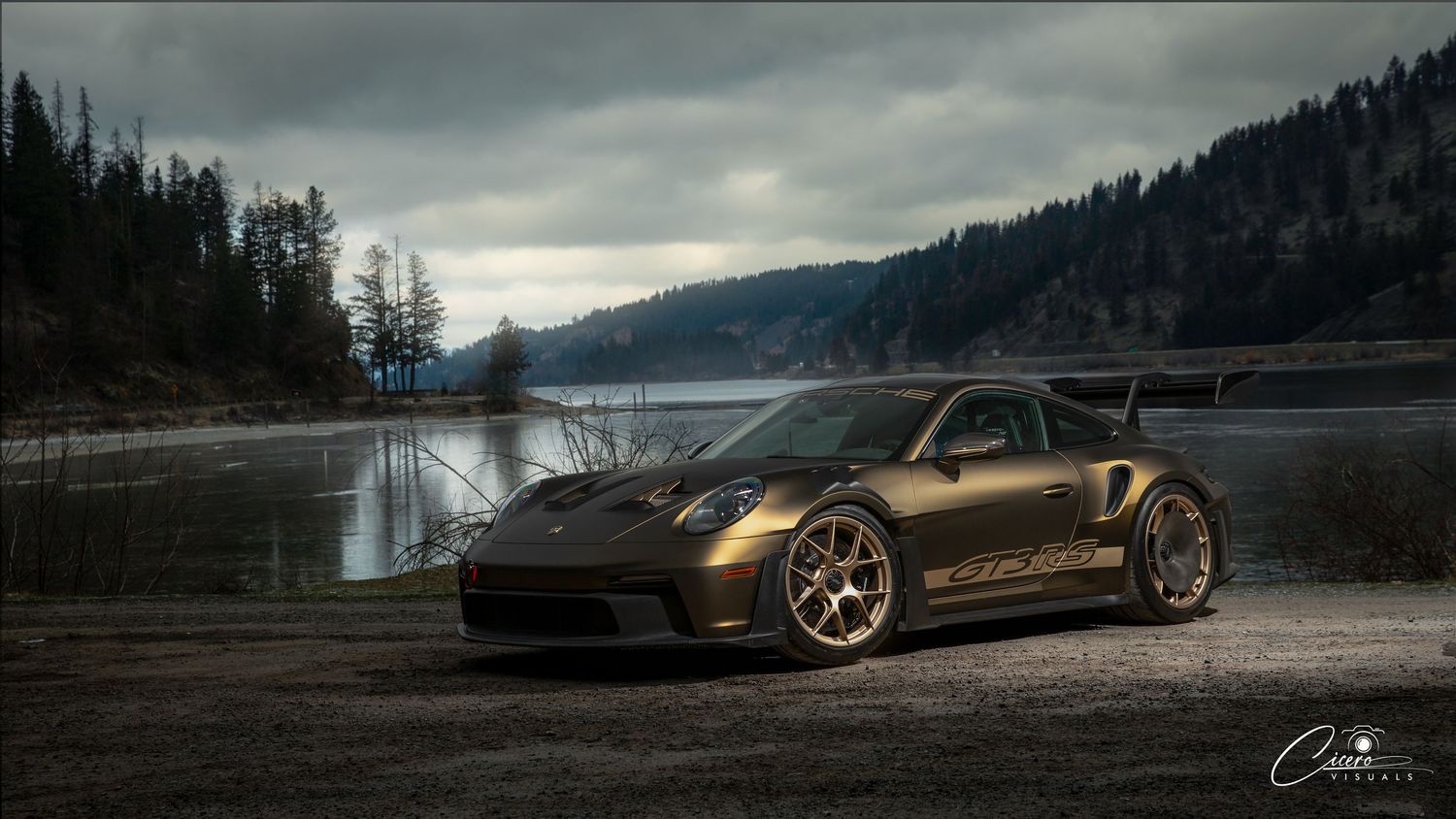 A modified Nissan 370Z sports car parked by a serene mountain lake under dramatic cloudy skies.