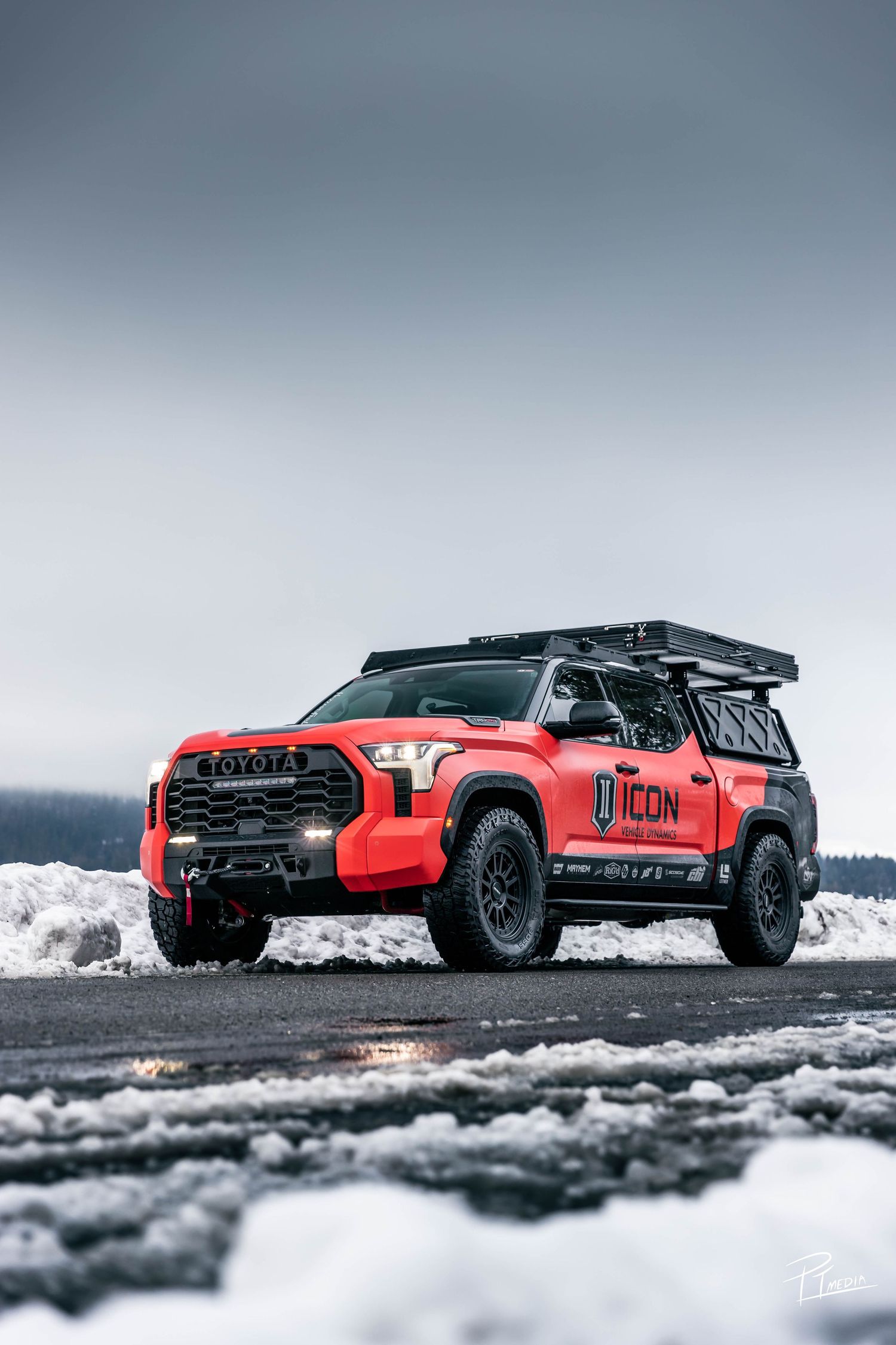 Red modified Toyota pickup truck driving through snowy terrain shown in multiple dynamic angles.