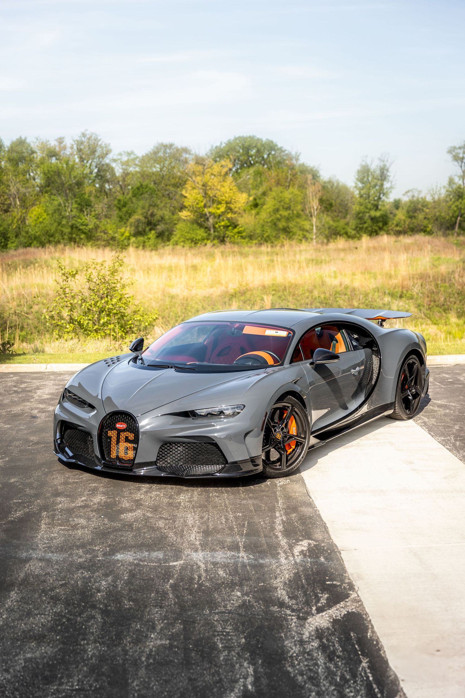 A sleek gray Bugatti Chiron photographed from multiple angles on a concrete surface against a natural backdrop.