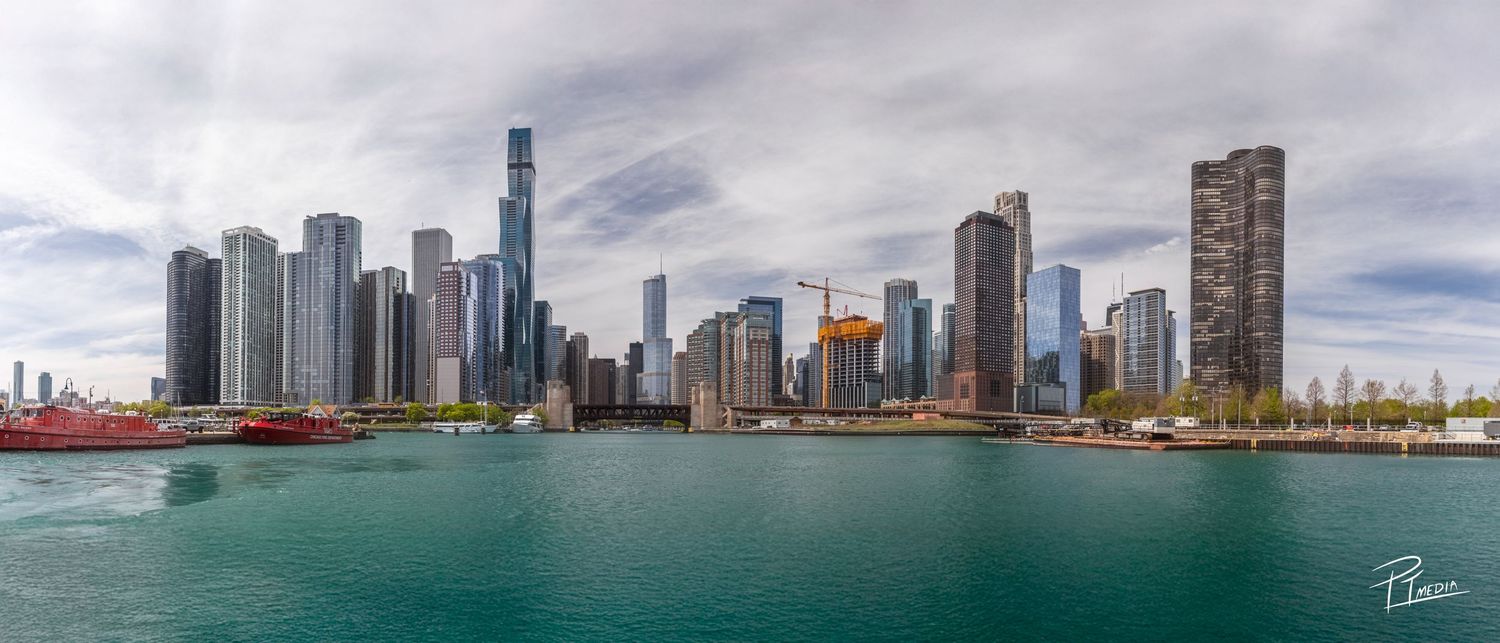 Panoramic view of Chicago's stunning skyline with modern skyscrapers reflecting in the turquoise waters of Lake Michigan.