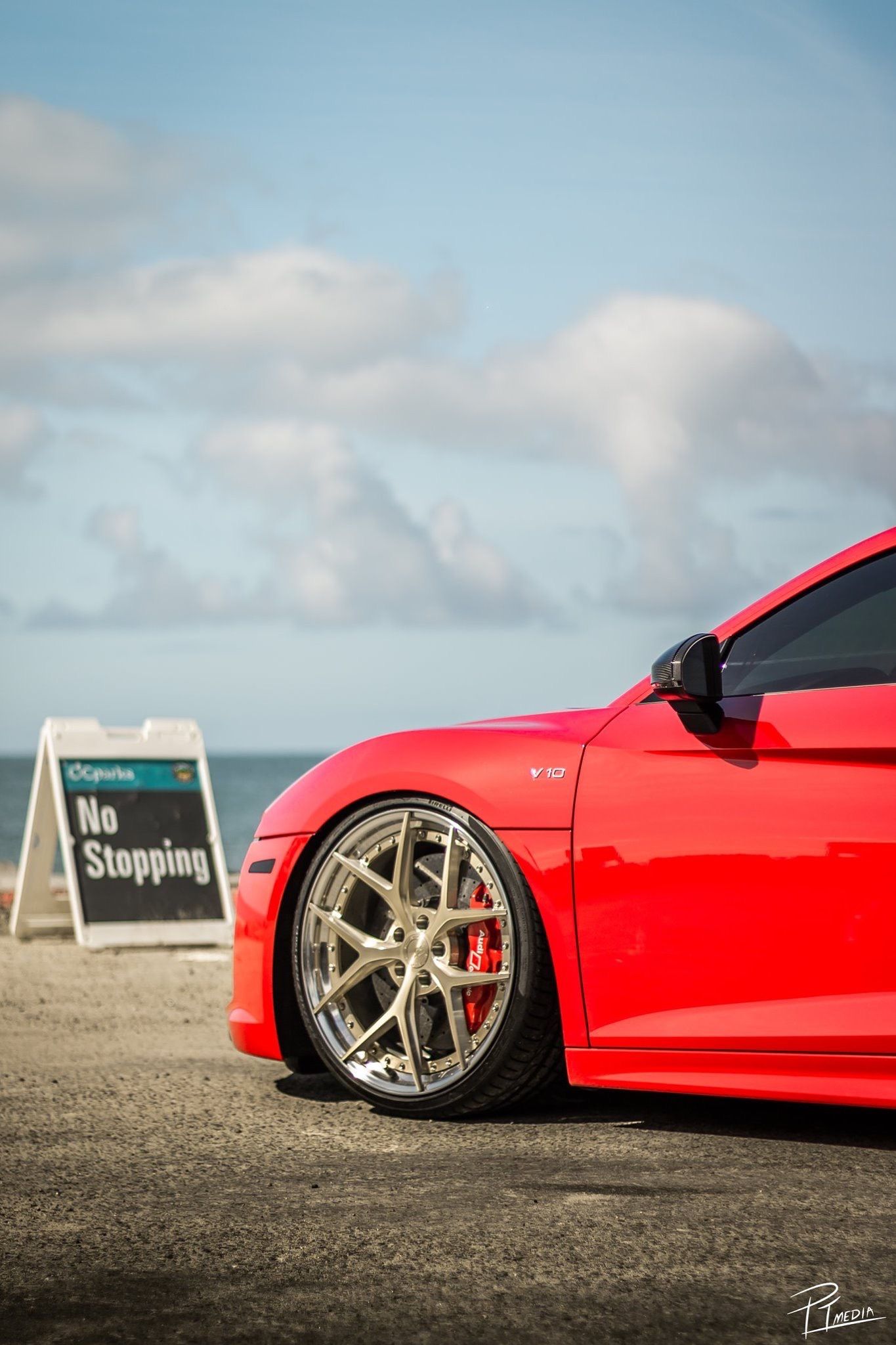 A red sports car with custom silver wheels shown in a sequence of low-angle detail shots against a cloudy sky background.