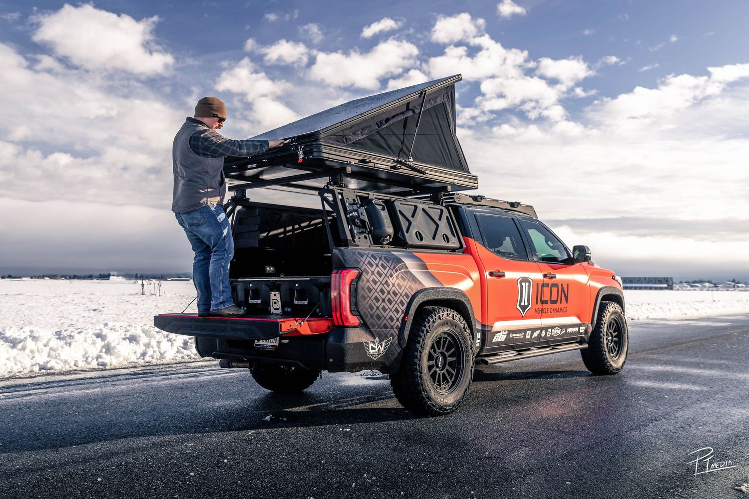 A sequence of action shots showing a pickup truck performing a high-speed jump on a snowy road against a cloudy sky.