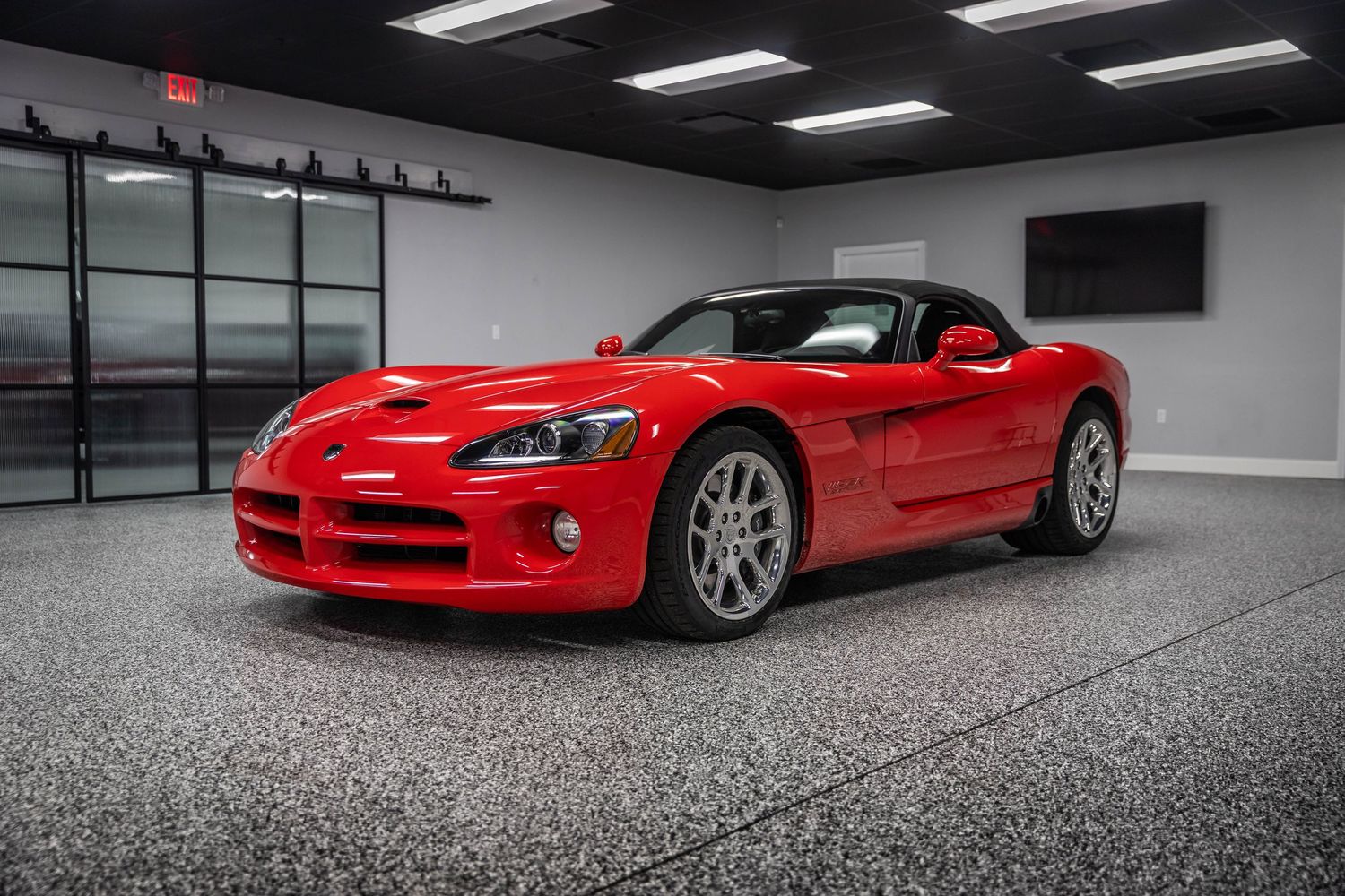 A red Dodge Viper sports car showcased in a modern showroom with dramatic lighting and polished floors.