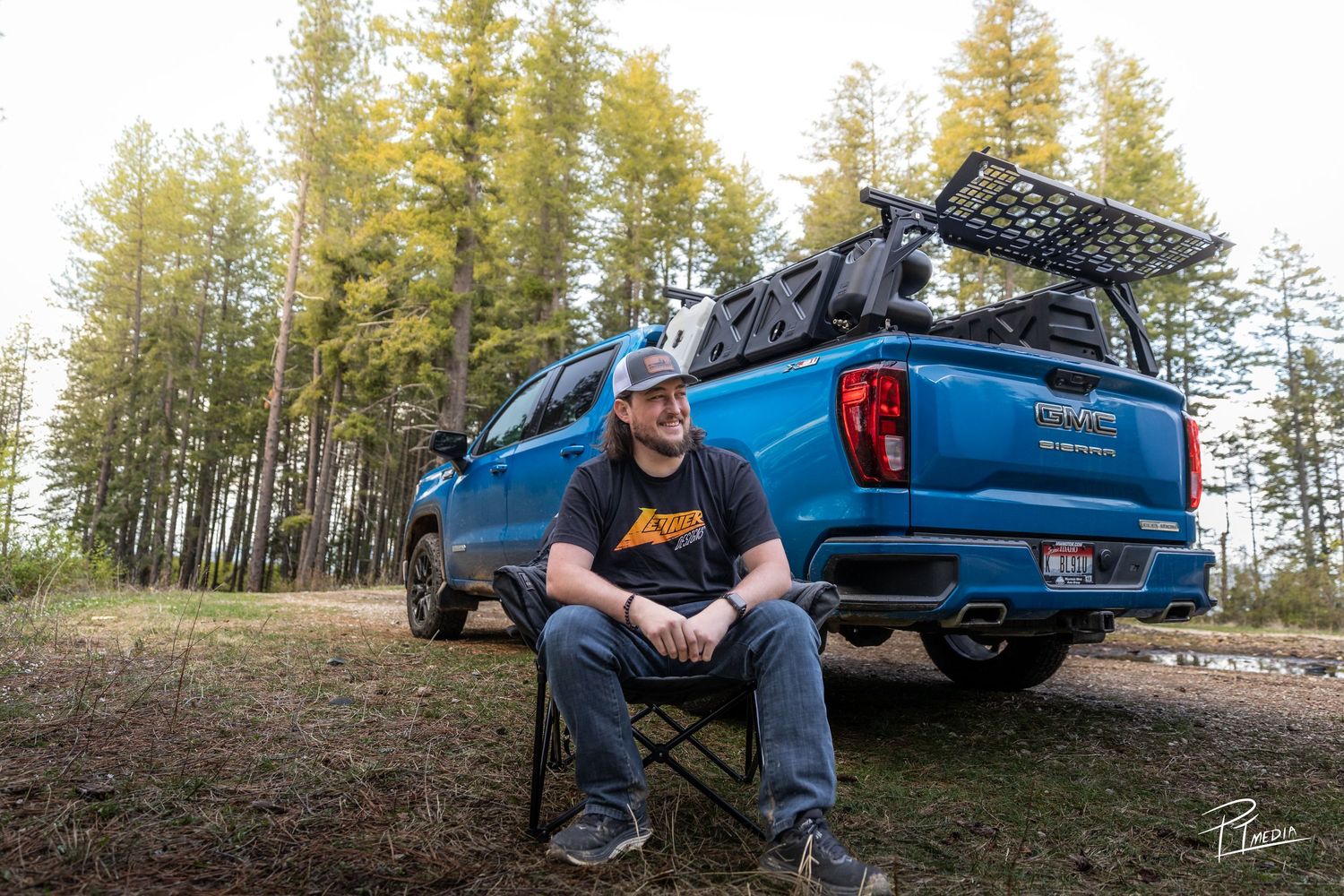 A blue pickup truck parked in a scenic forest setting with evergreen trees in the background.