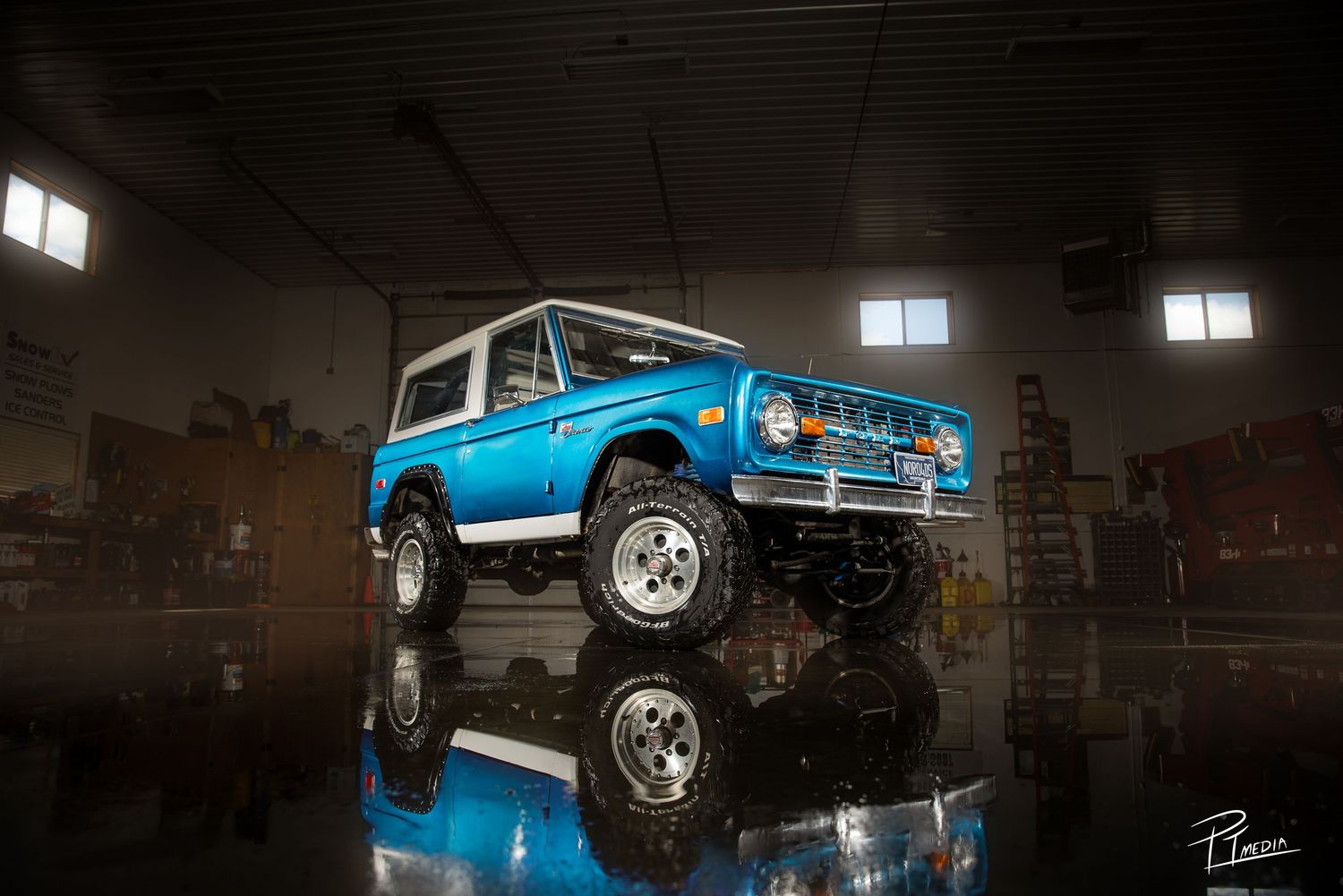 A bright blue vintage Ford Bronco shown from multiple angles in a dark indoor setting with dramatic lighting.