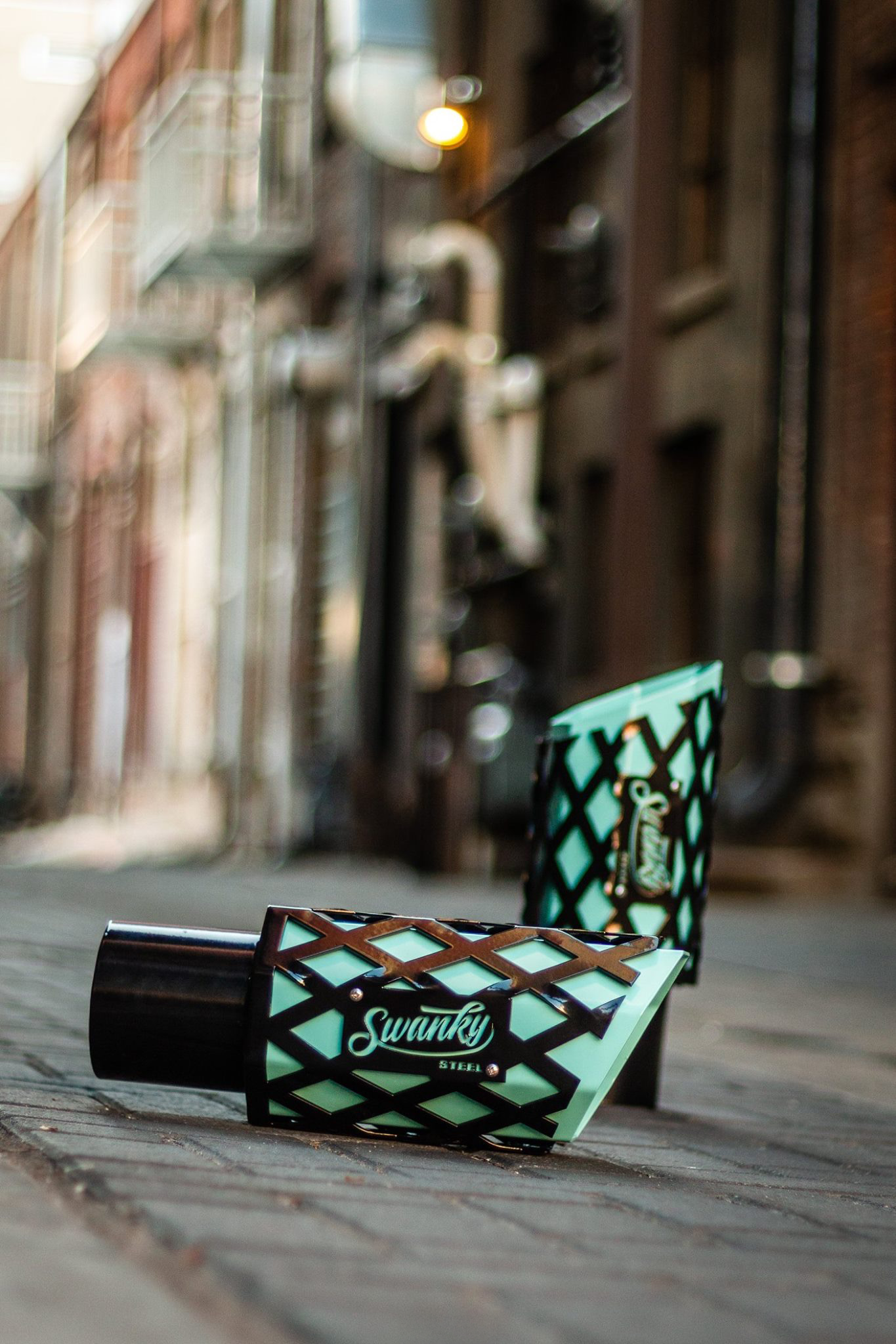 Turquoise Suavecito hair styling products displayed on wooden surface with urban backdrop.