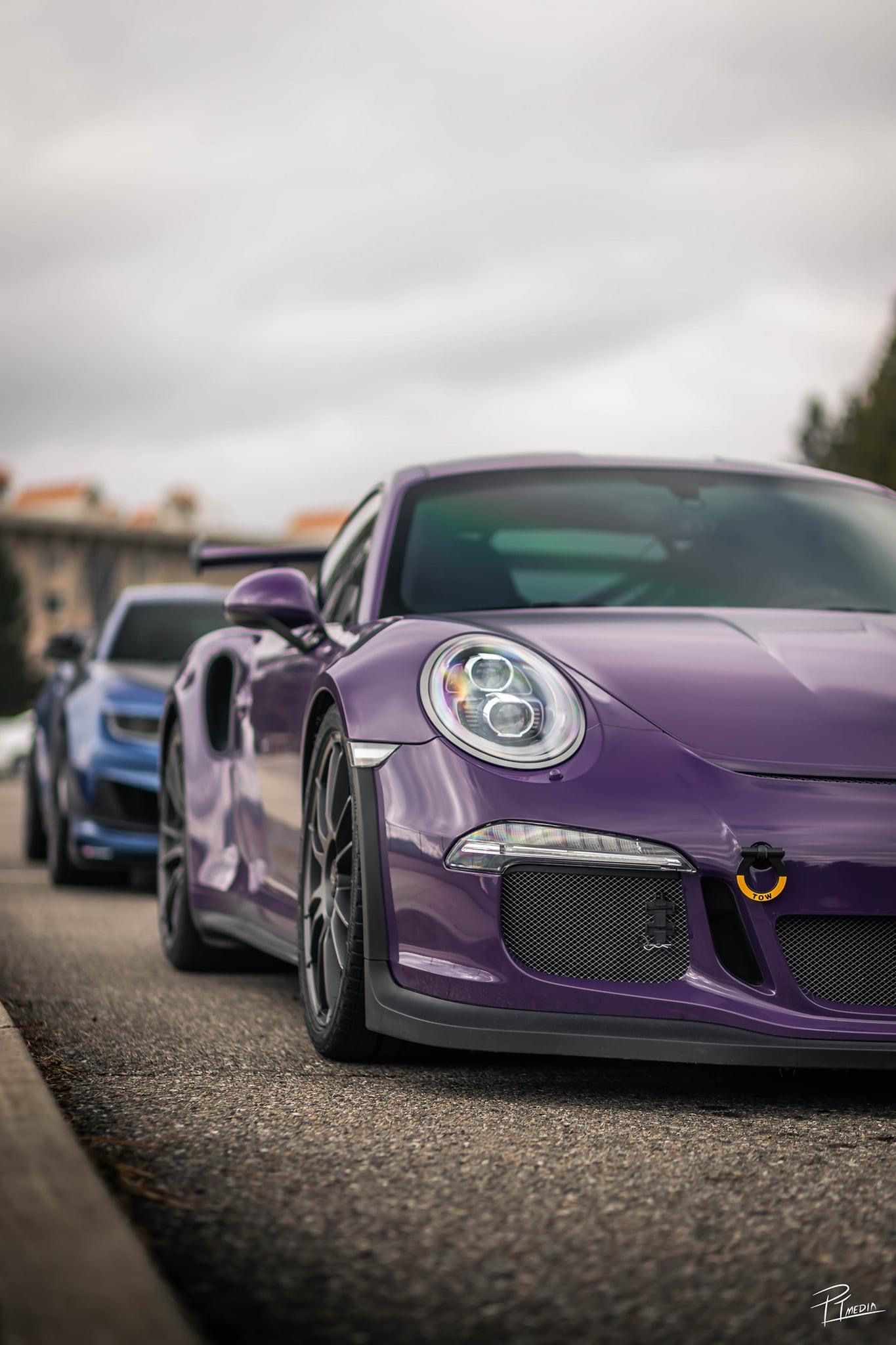 Close-up view of a purple Porsche 911 GT3 with distinctive headlights and front grille on a cloudy day.