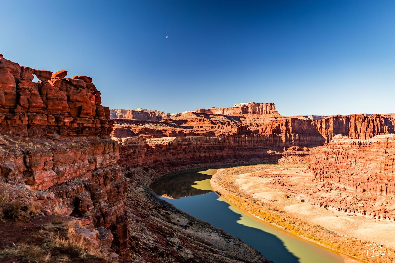 Scenic aerial view of Lake Powell's winding blue waters contrasting with red sandstone cliffs under clear skies.