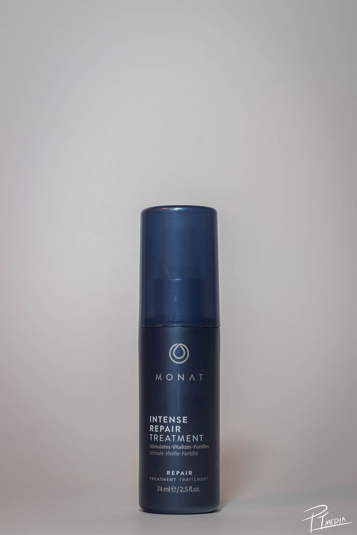 Navy blue Monat hair treatment product bottle shown from different angles against a light gray background.