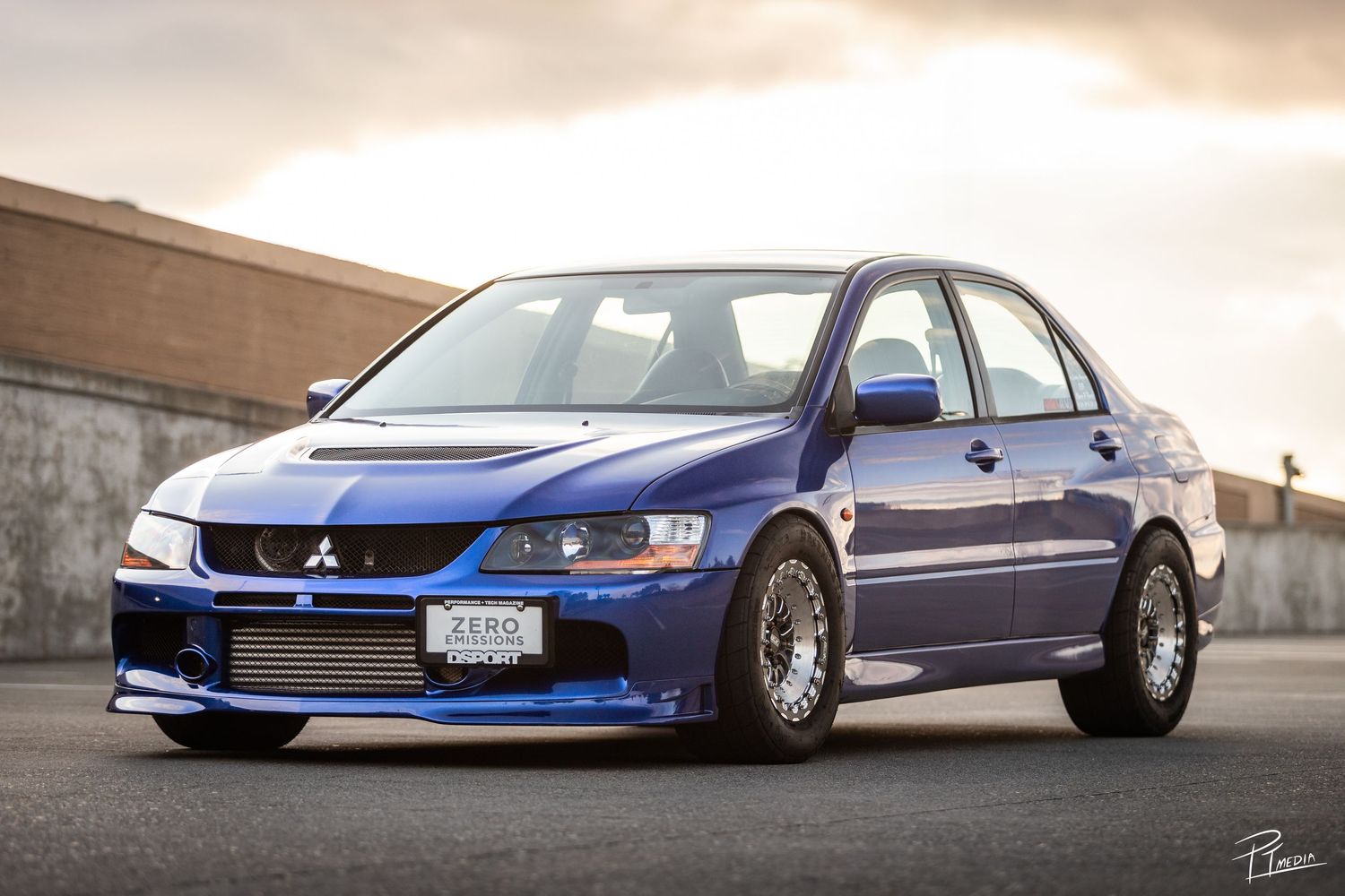 A lowered blue Mitsubishi Evolution sports car shown from multiple angles against a cloudy sky backdrop.