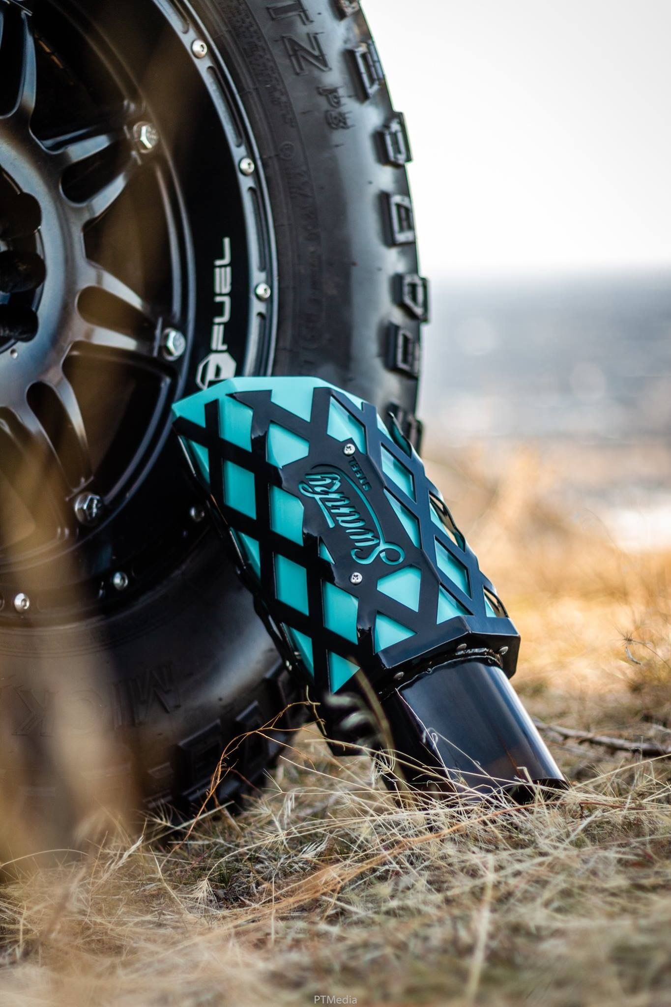 Close-up view of black and turquoise roller skate wheels on dry grass during sunset.
