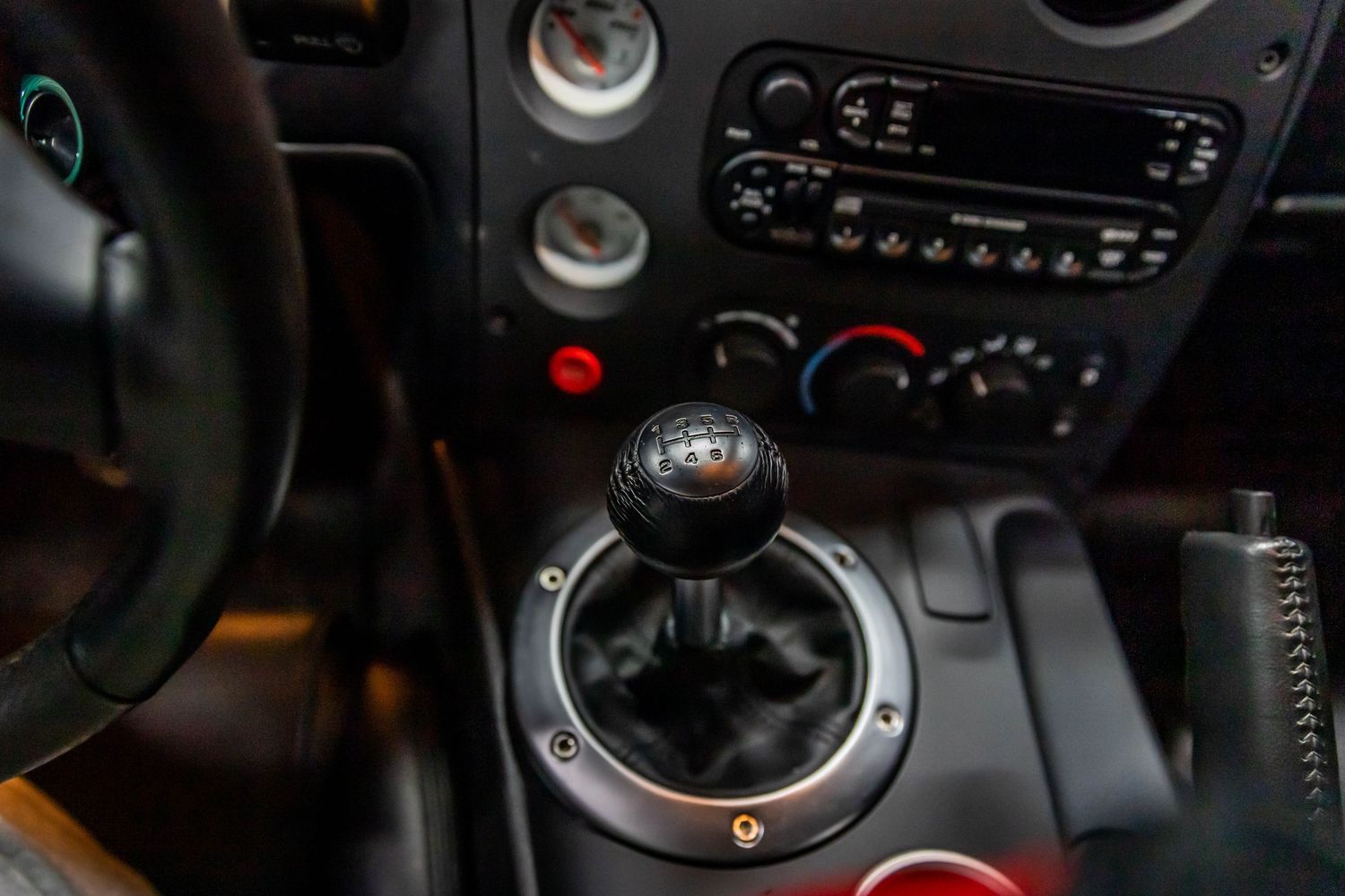 Close-up view of a manual gear shift knob and transmission in a car interior.