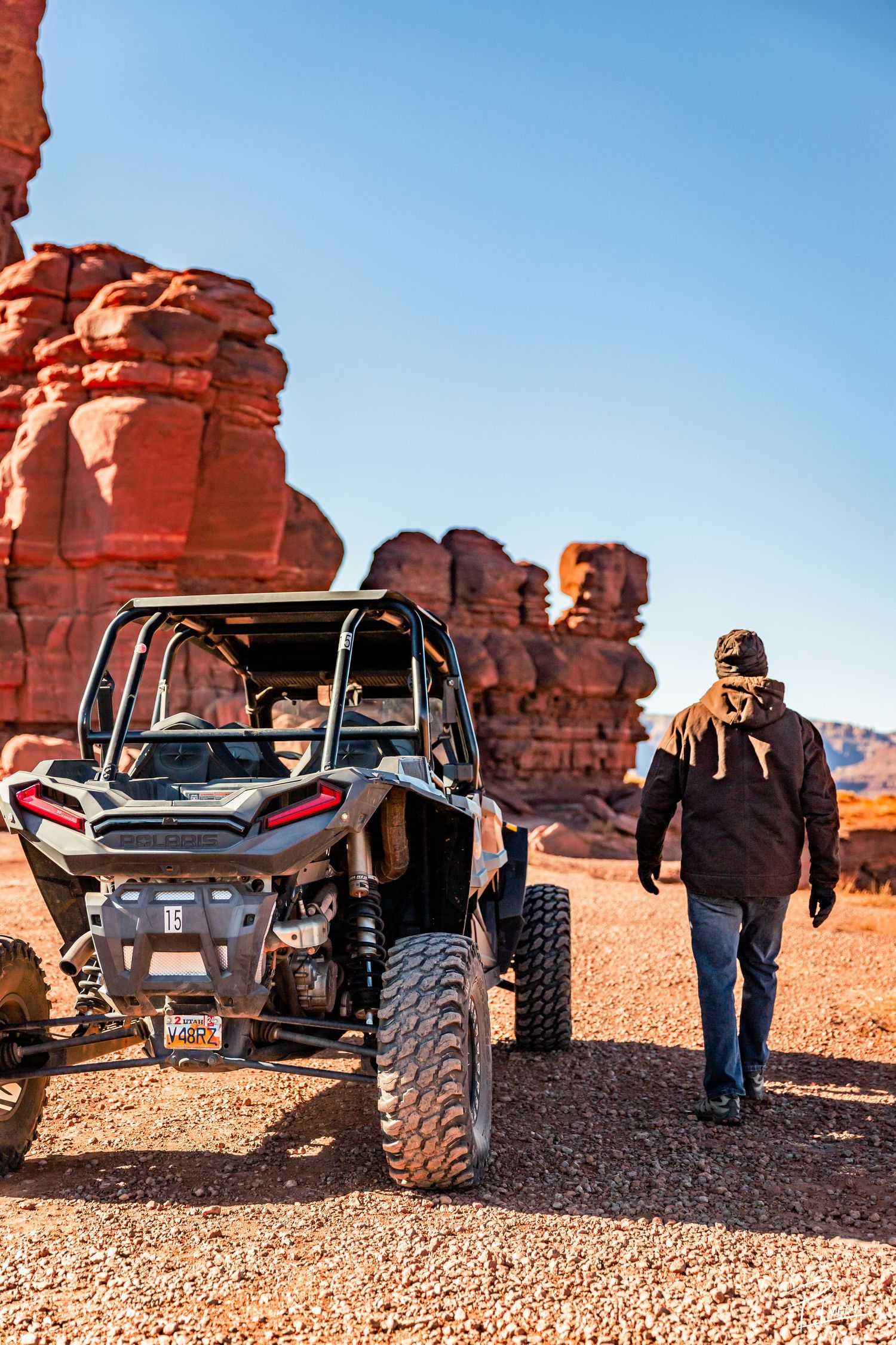 Off-road utility vehicle parked near red rock formations in desert landscape during sunny day.