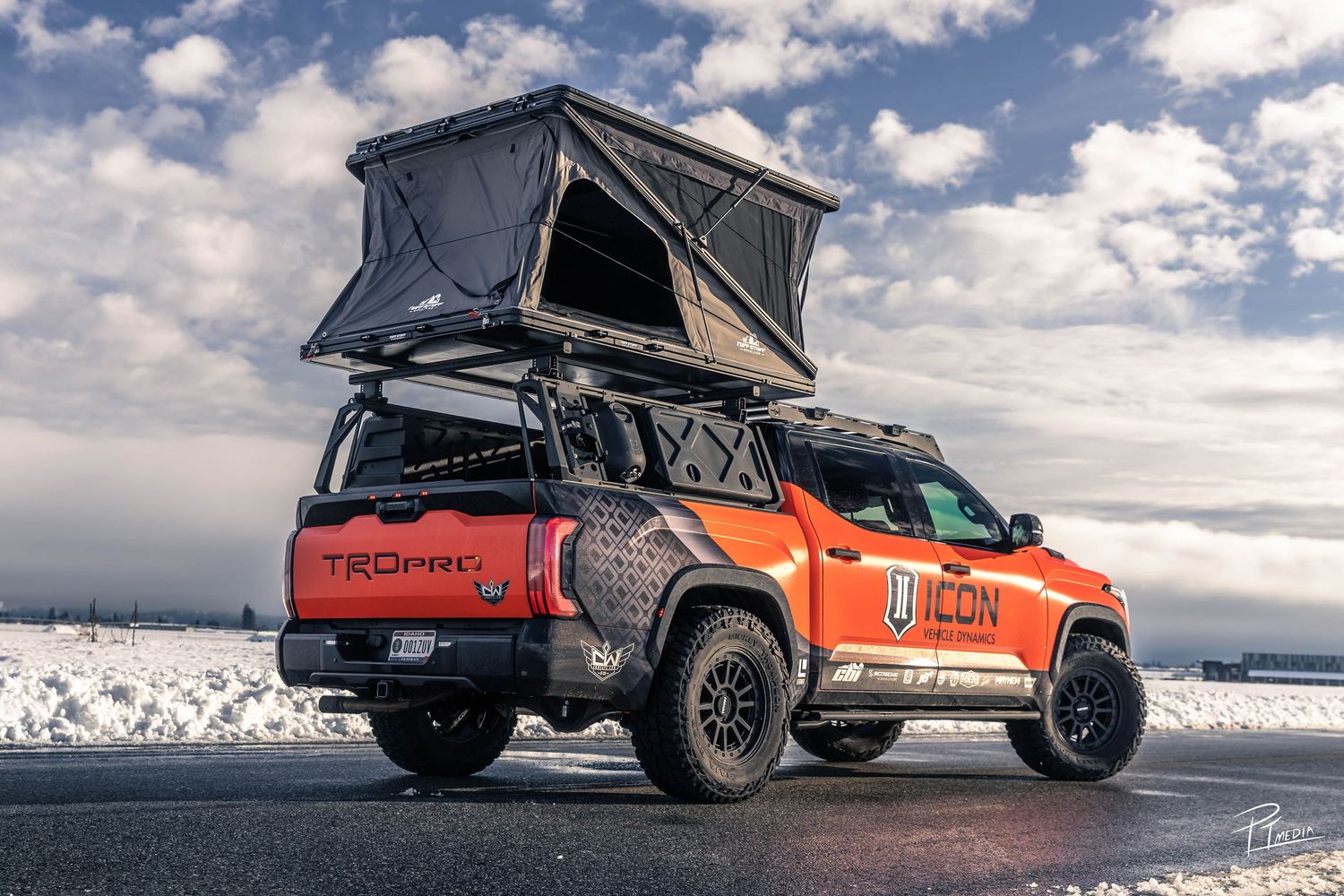 Orange rooftop tent camper vehicle shown in multiple angles against dramatic cloudy skies and snowy landscapes.