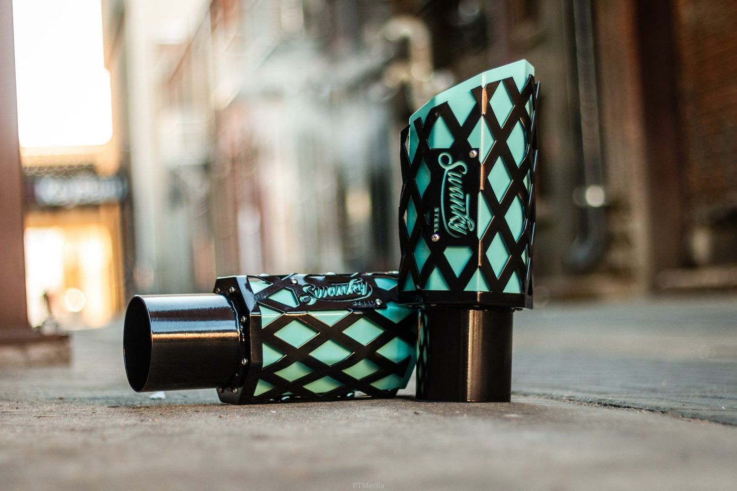 Turquoise and black patterned vape device lying on wooden surface with blurred background.