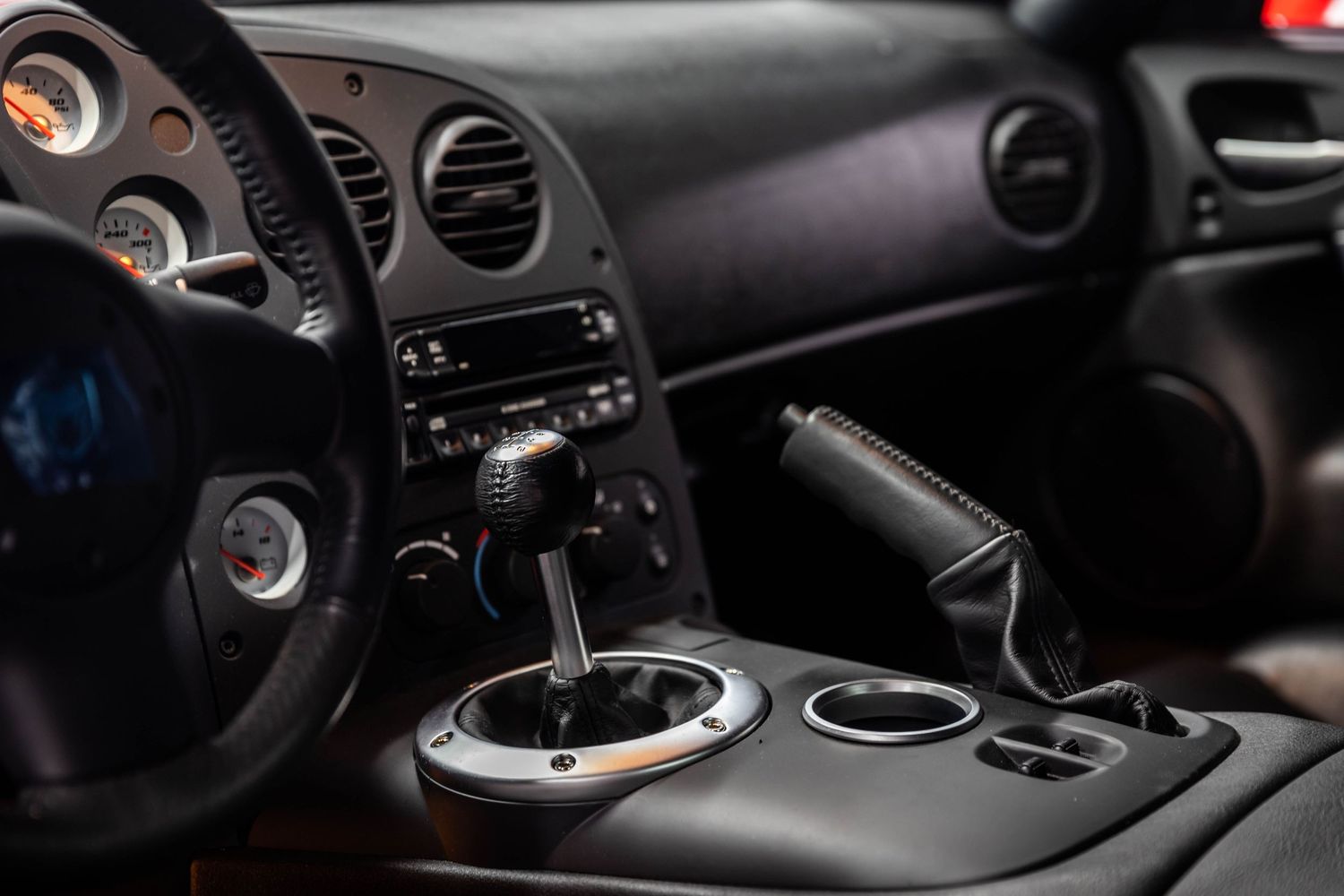 Interior view of a modern car dashboard showing gear shifter, climate vents and dark upholstery details.