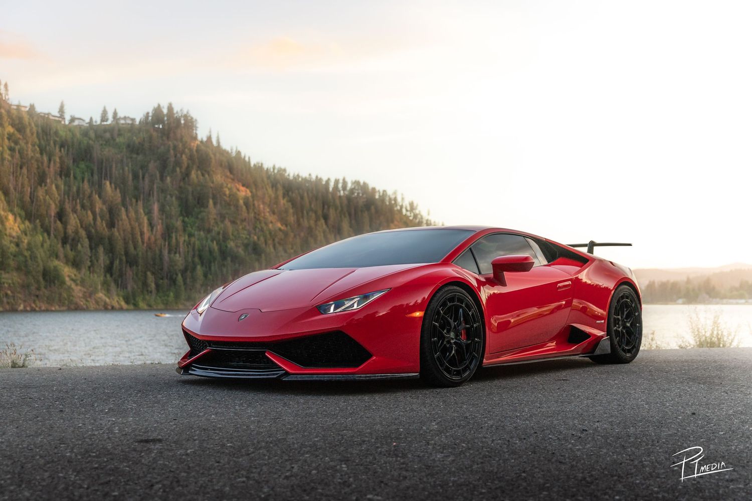 A collection of red supercars photographed at sunset against scenic mountain and lake backdrops.