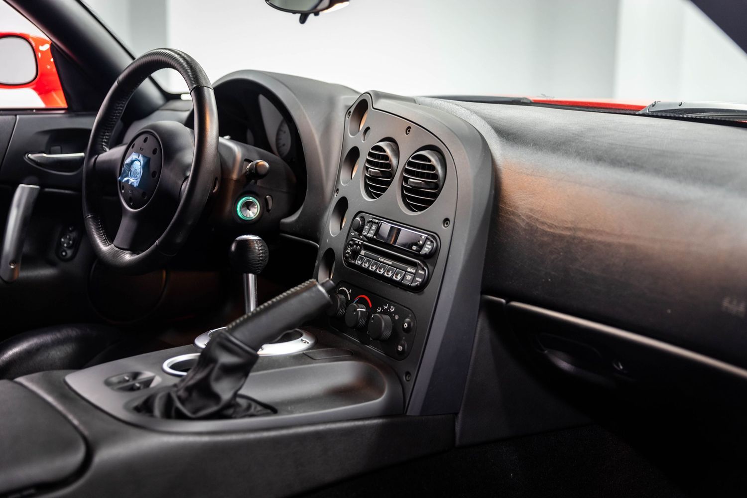 Interior view of a car dashboard showing controls, steering wheel, and instrument panel in dark lighting conditions.