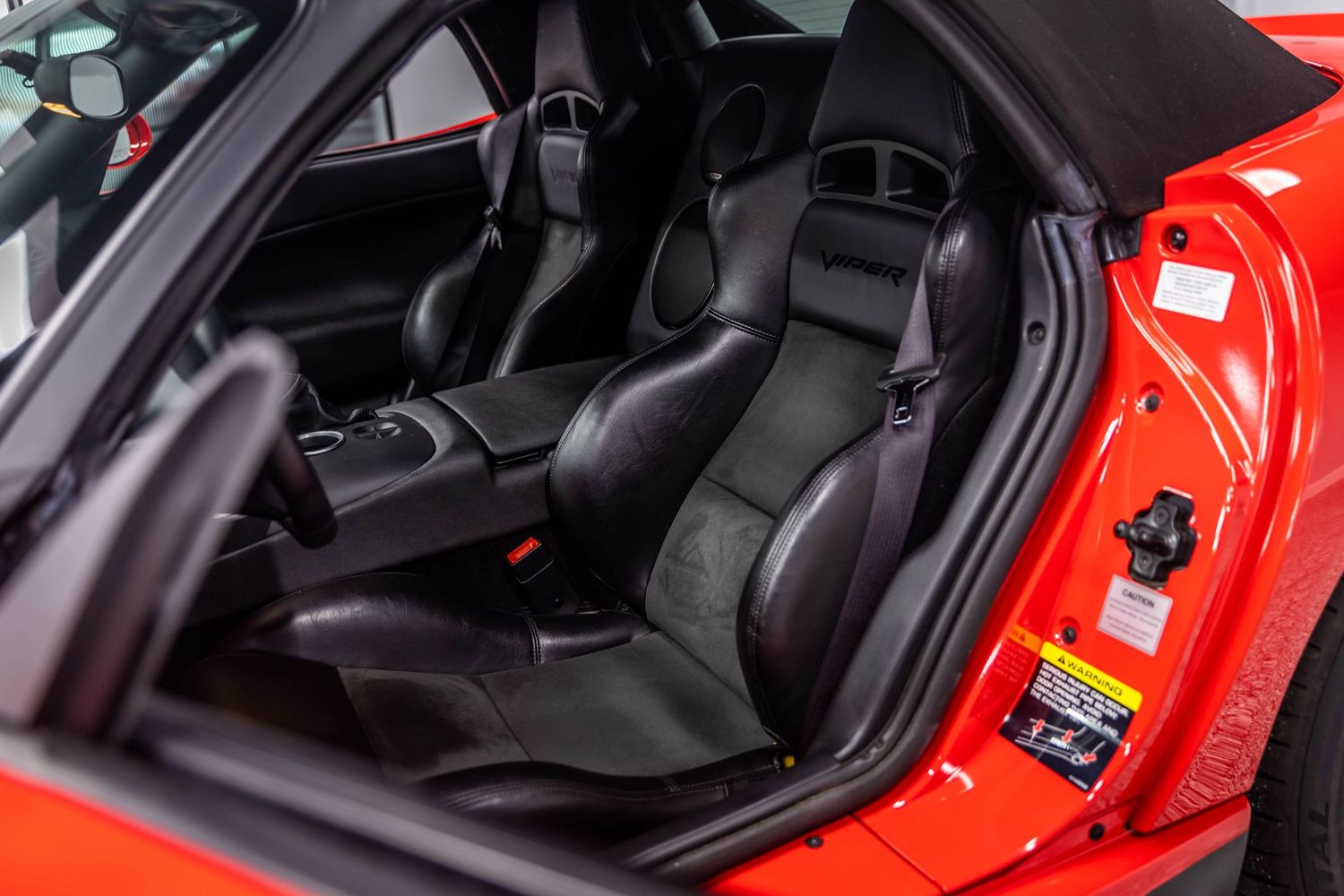 Interior view of a red Ferrari sports car showing black leather seats and modern dashboard controls.