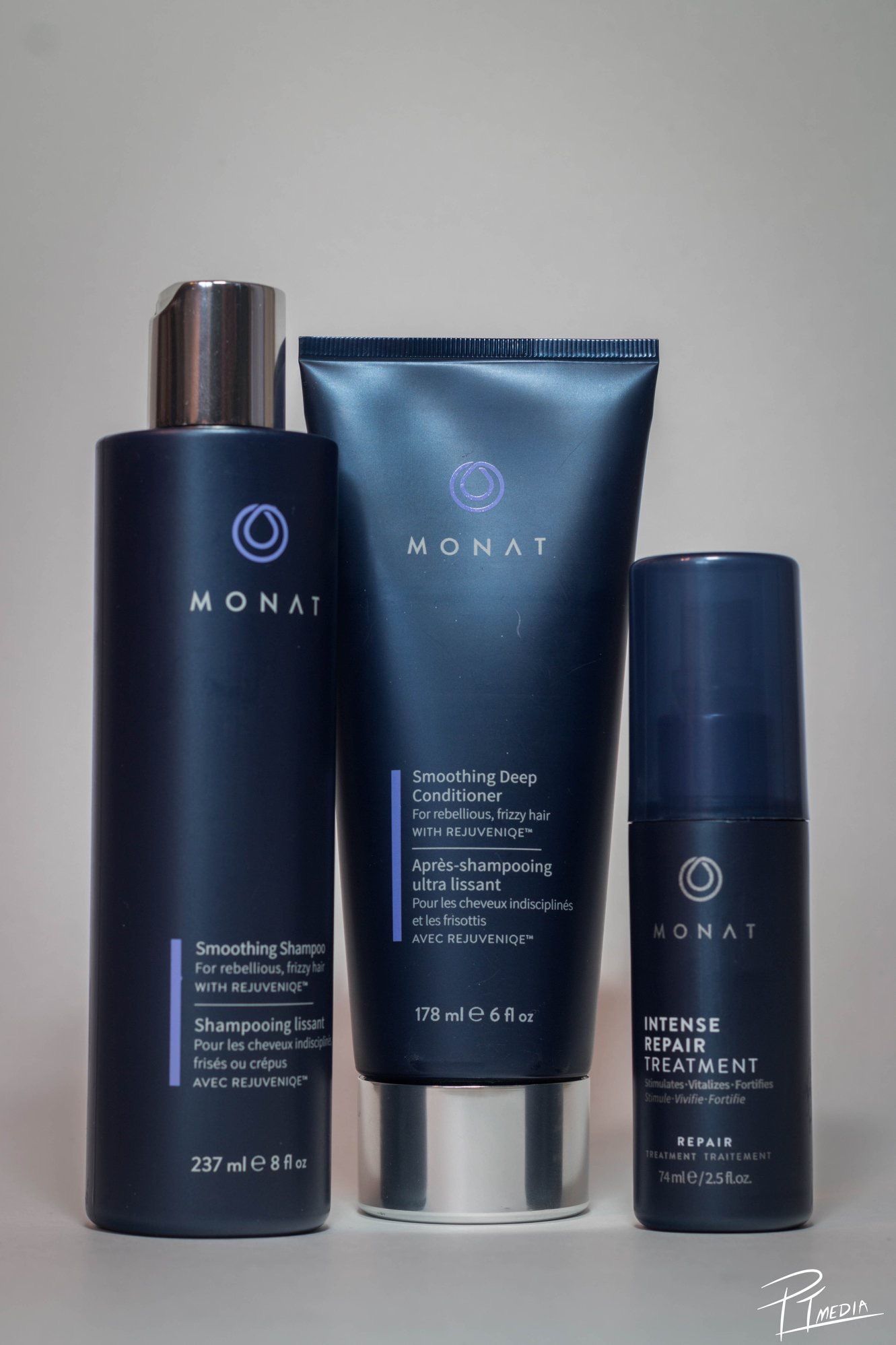 Collection of Monat hair care products in sleek dark blue packaging arranged in a minimalist display.