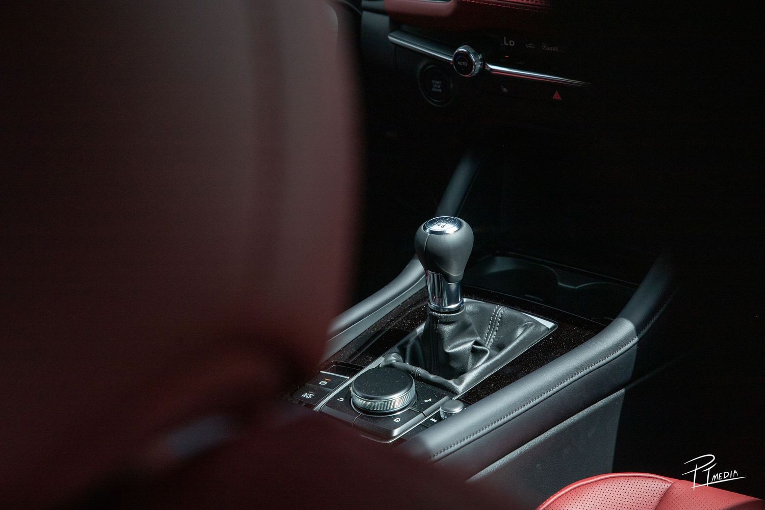 Interior view of a modern car showing the automatic transmission gear shifter with dark interior trim details.
