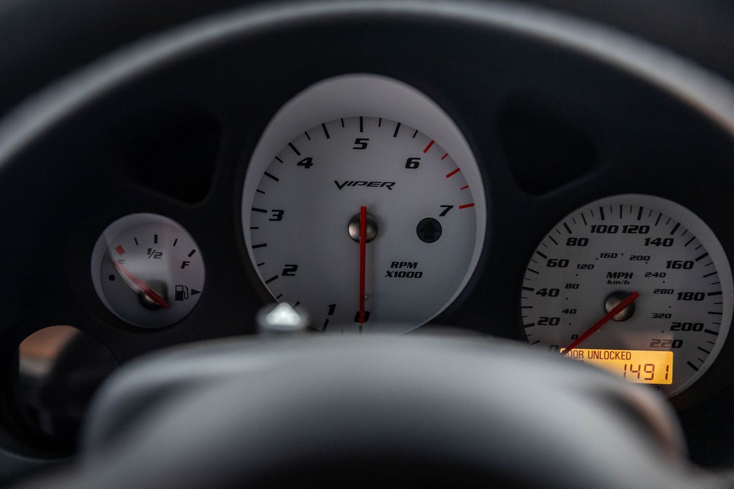 Close-up view of a car dashboard showing illuminated gauges and instrument cluster displays in low light conditions.