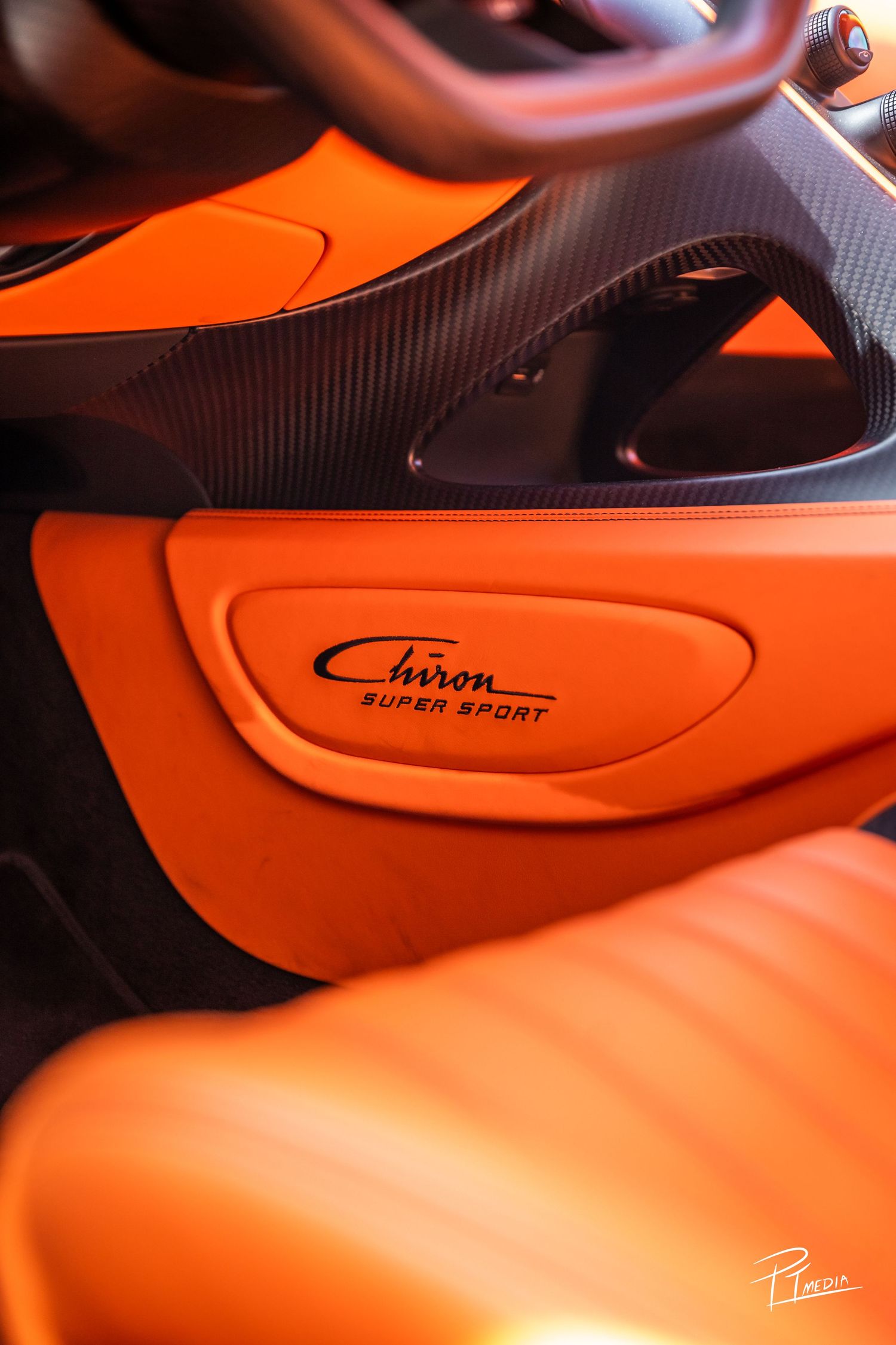 Close-up view of sleek orange and black carbon fiber sports car body panels with smooth curves and contours.