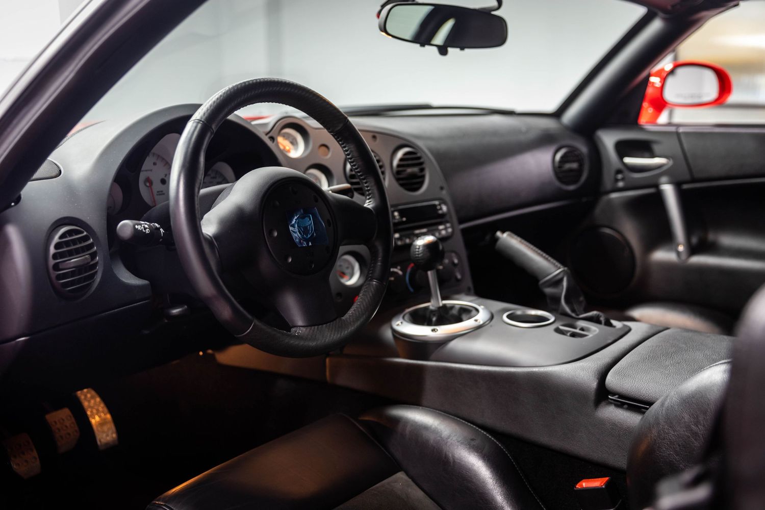 Interior view of a modern car dashboard showing steering wheel, instrument panel and center console in dark tones.