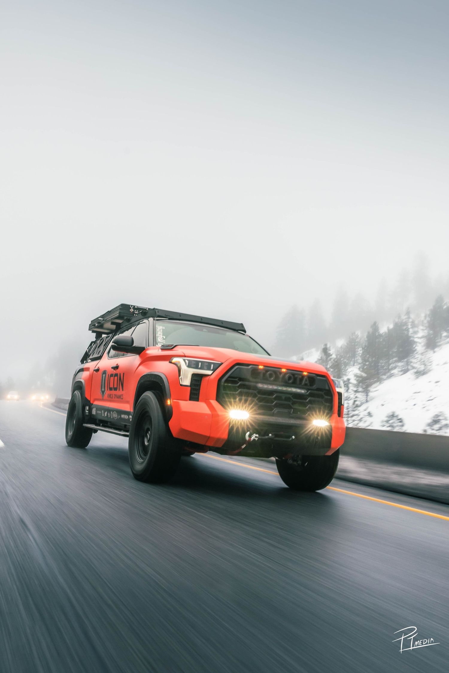 Orange sports car drifts on snowy mountain road through misty winter conditions in dramatic action sequence.
