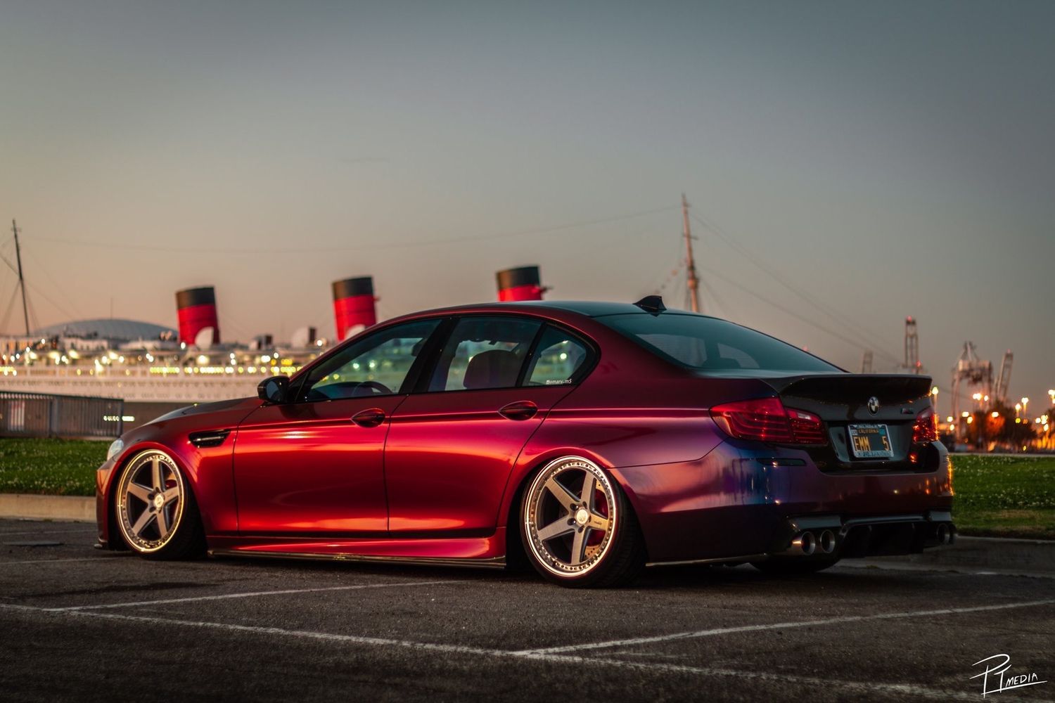 A red luxury sports car photographed at sunset showcasing its sleek profile and custom wheels.
