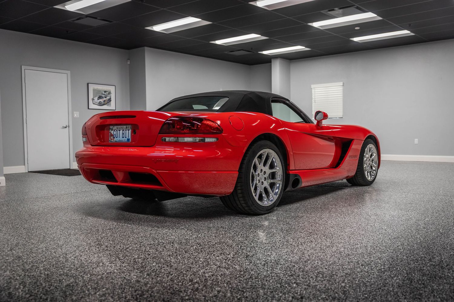 A red sports car photographed from multiple angles in a minimalist white garage space with fluorescent lighting.