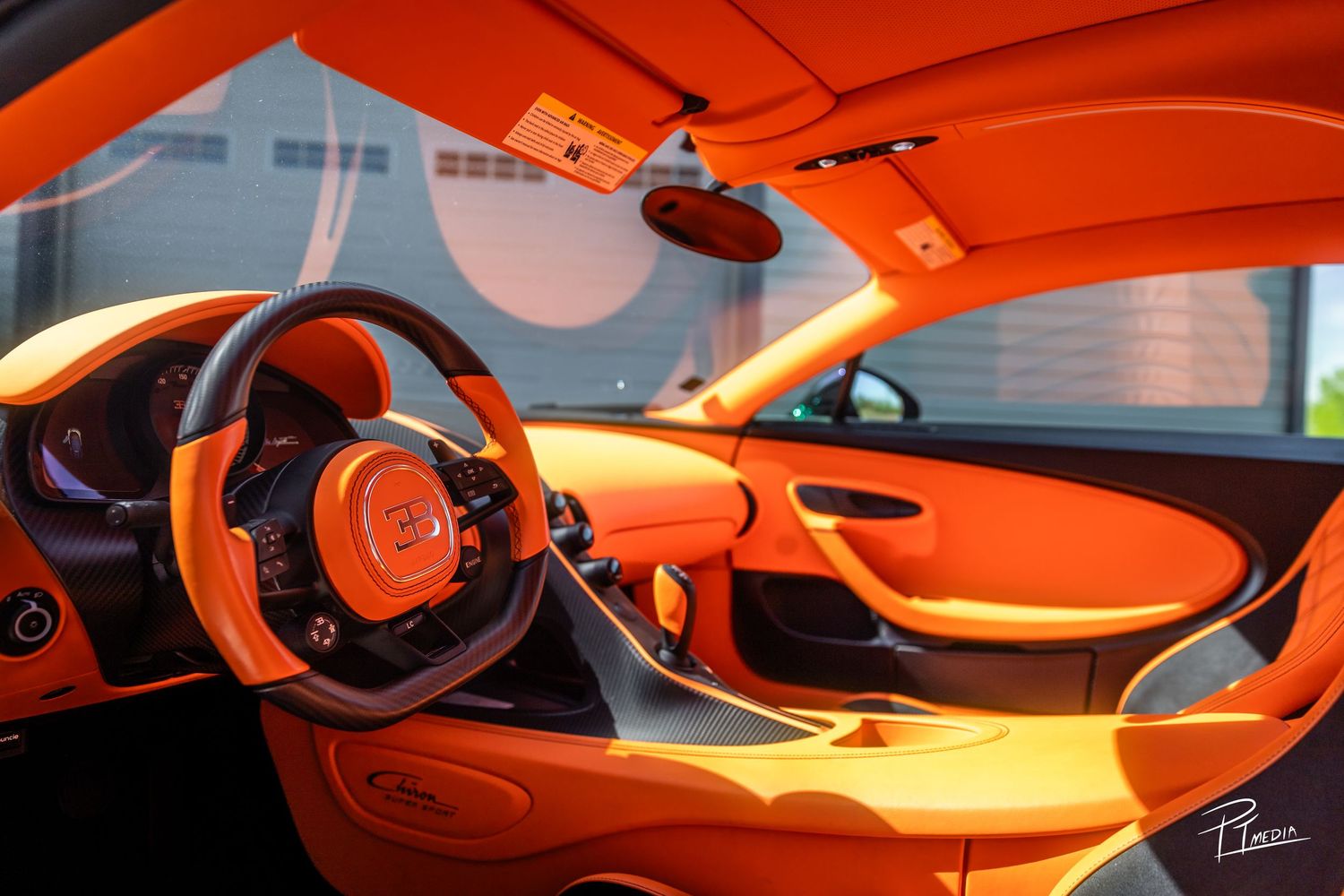 Interior view of a bright orange McLaren supercar cockpit showing sleek dashboard and steering wheel details.