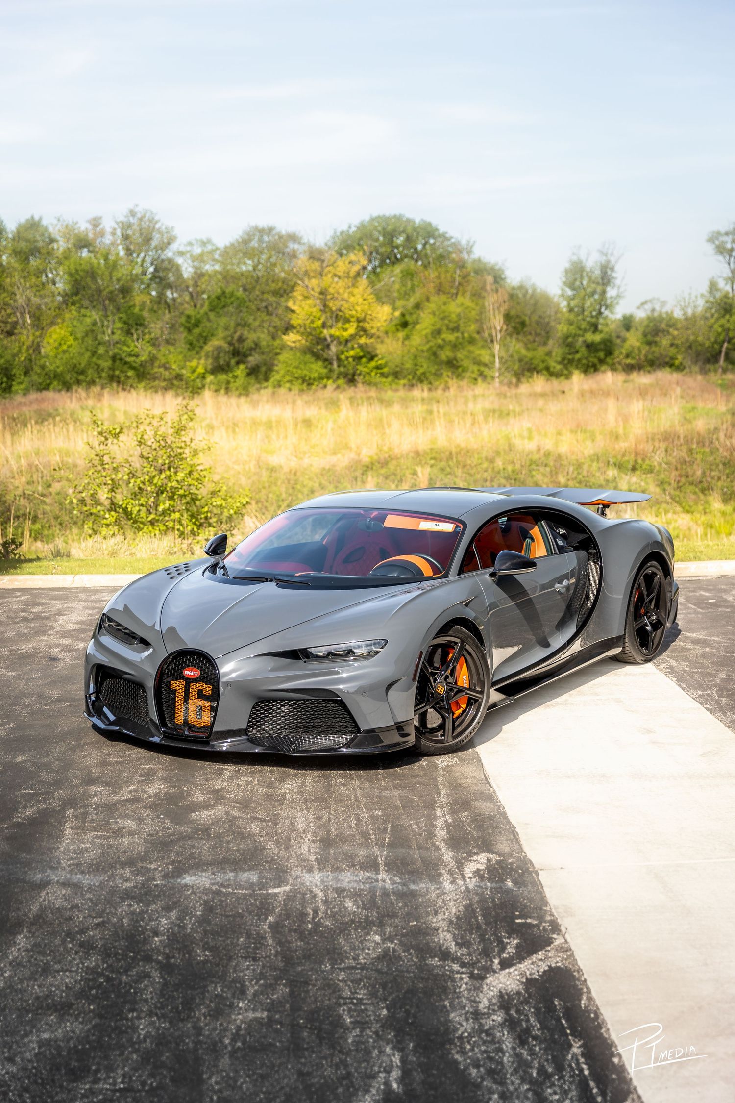 A sleek gray Bugatti supercar photographed from multiple angles on a concrete surface against a natural backdrop.