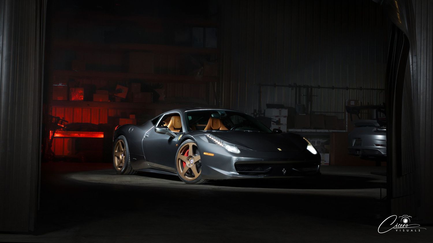 A sleek grey Ferrari 458 photographed in a dramatic low-light setting with glowing red taillights in Coeur d' Alene, Idaho