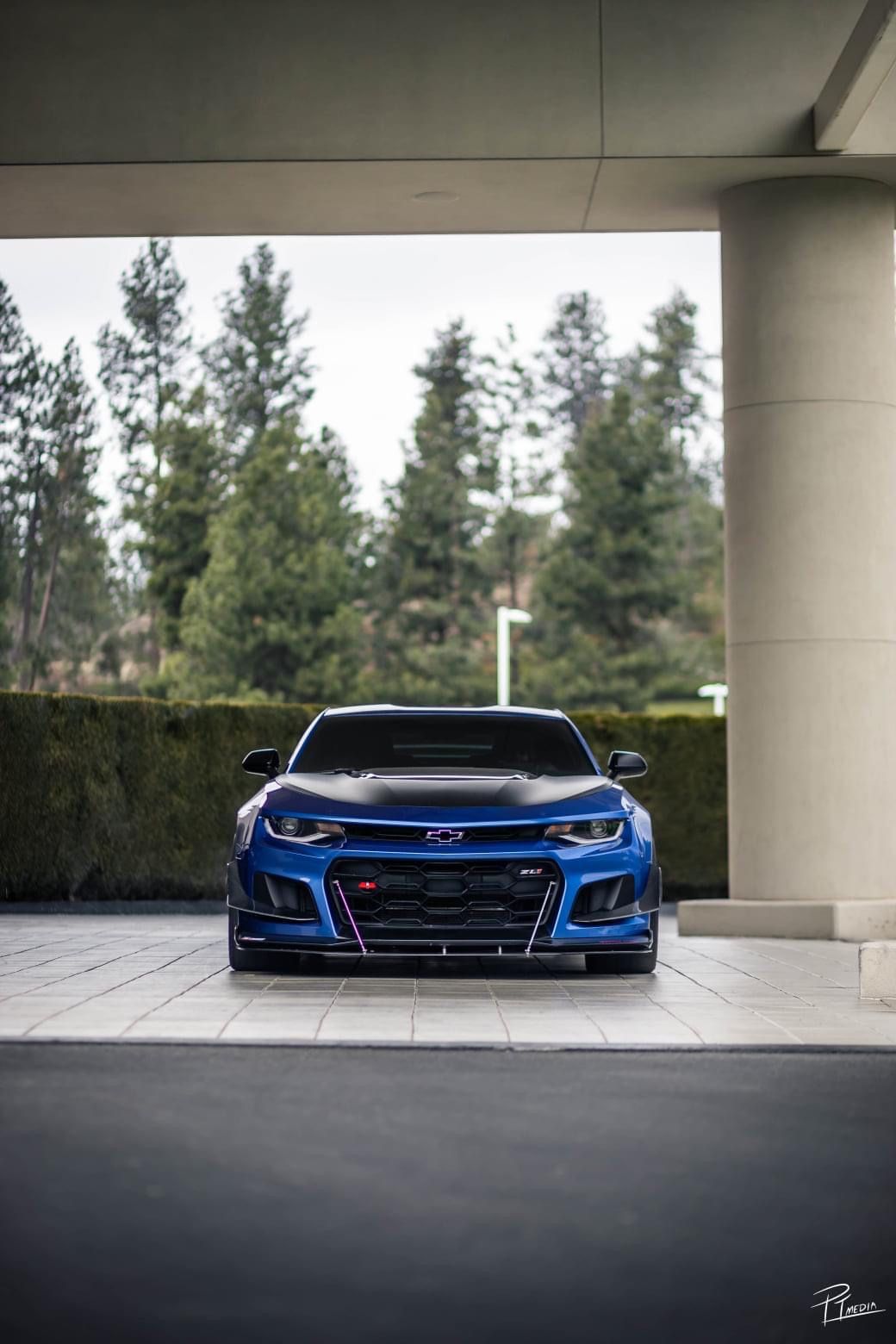A sleek blue Chevrolet Camaro ZL1 photographed in a dramatic low angle sequence under concrete pillars.