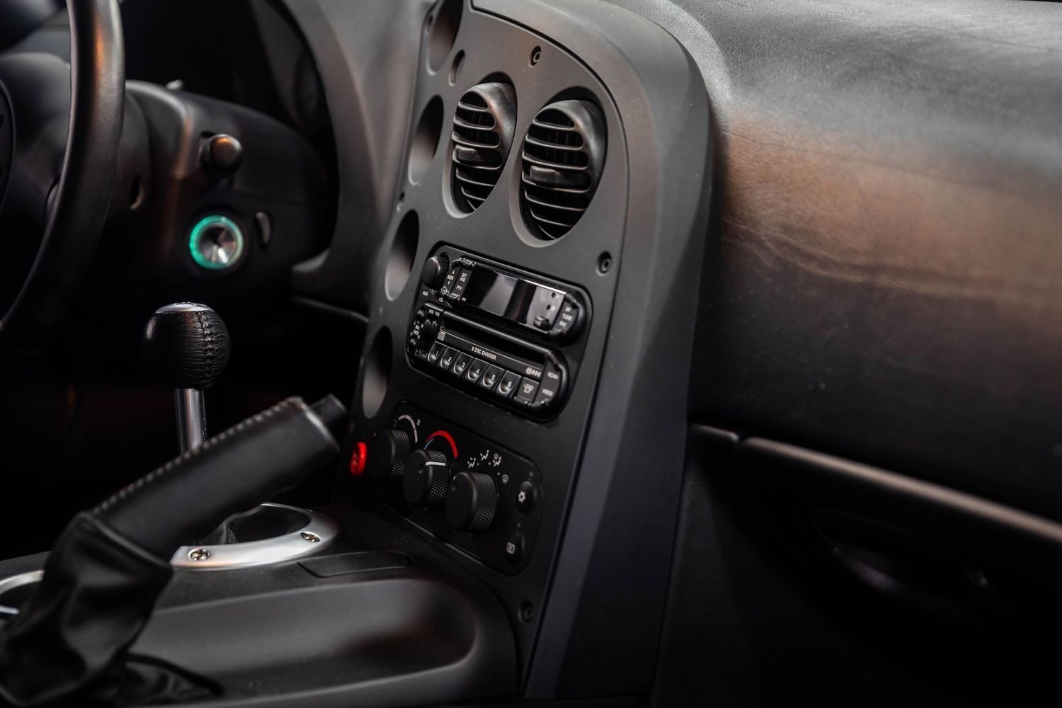 Interior view of a car dashboard showing air vents, climate controls and center console in dark gray tones.