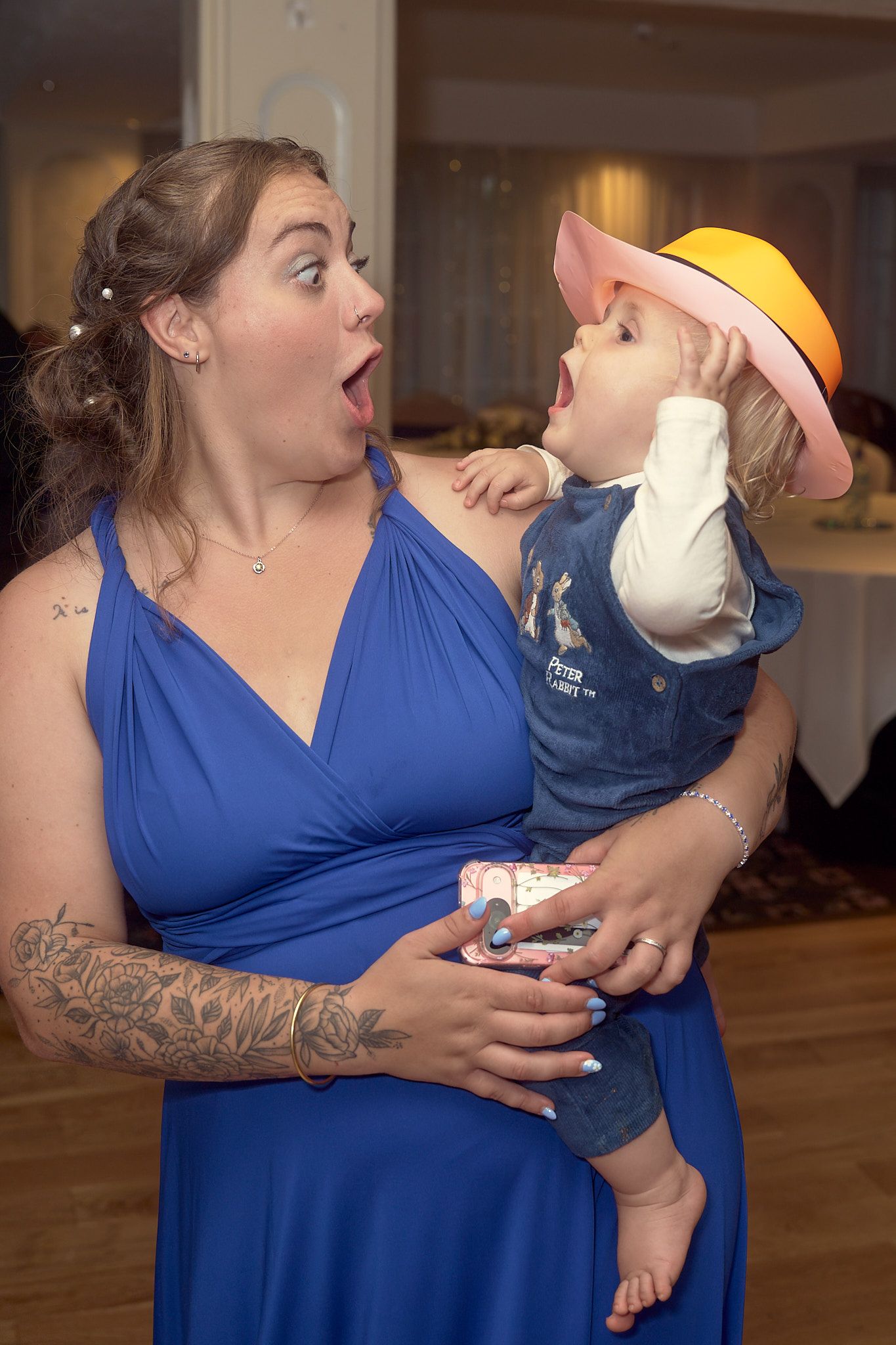 Woman in a blue dress sharing a playful moment with a young child at a wedding reception.