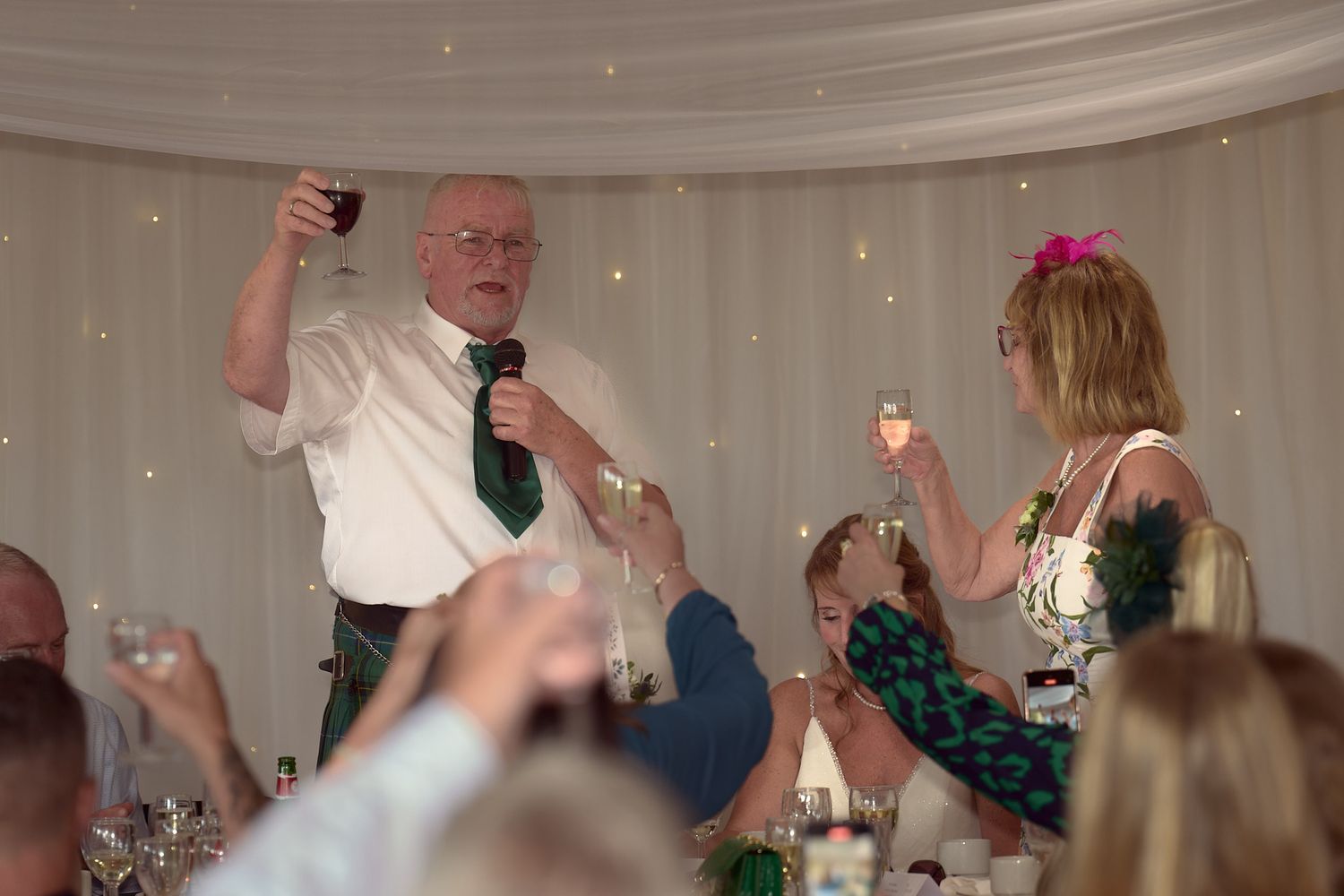Groom raising a glass while giving a speech at the reception.