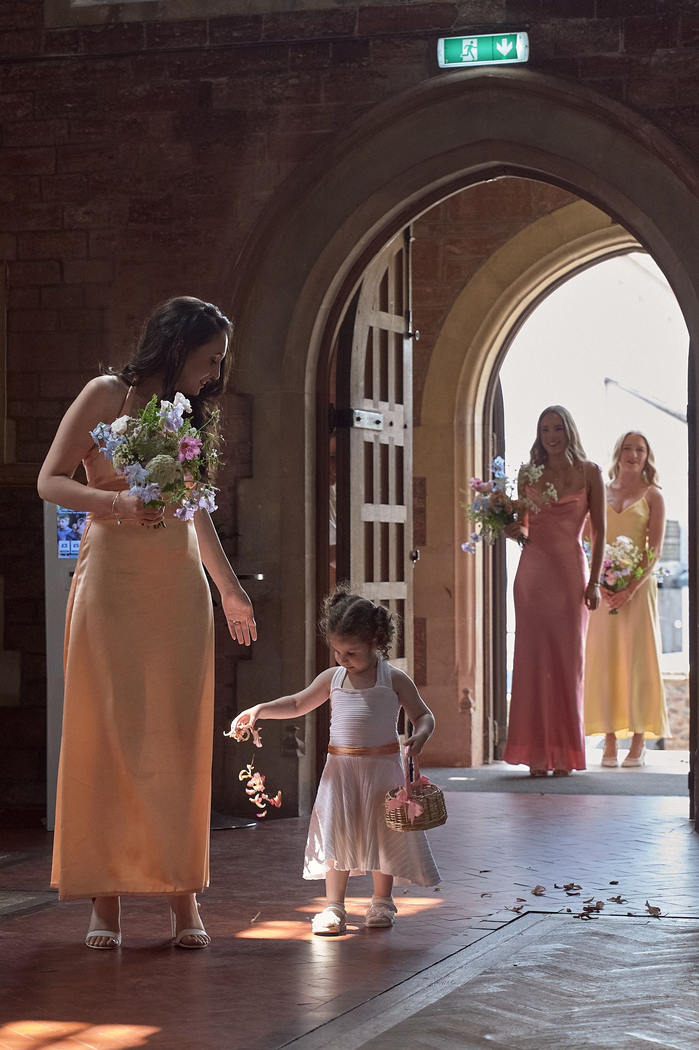 Bridesmaid entering through the church doorway as guests look on.