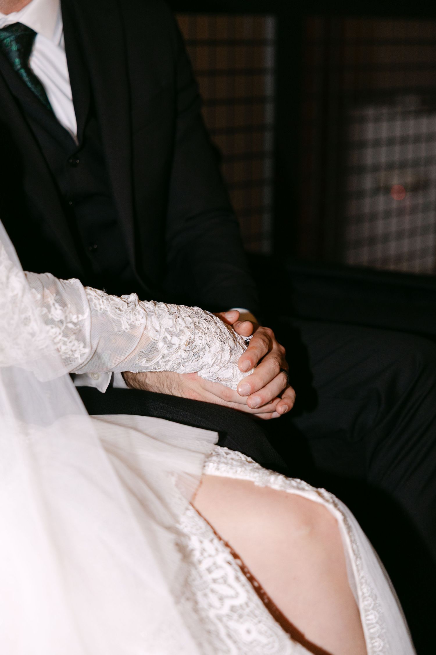 Close-up view of a bride's white lace sleeve detail and garter being adjusted during a wedding ceremony.