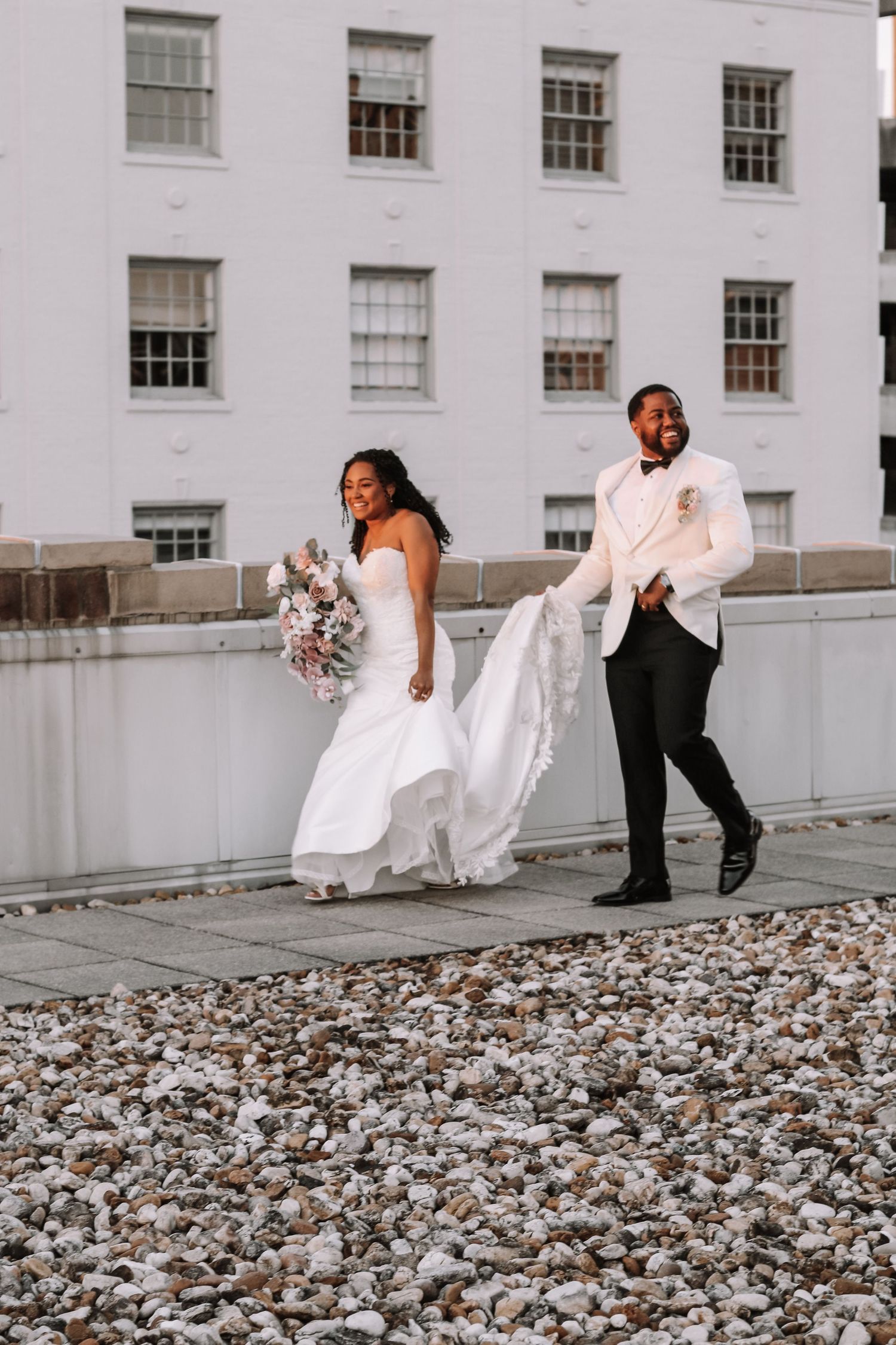 Wedding couple walking across a rooftop covered in white stones.