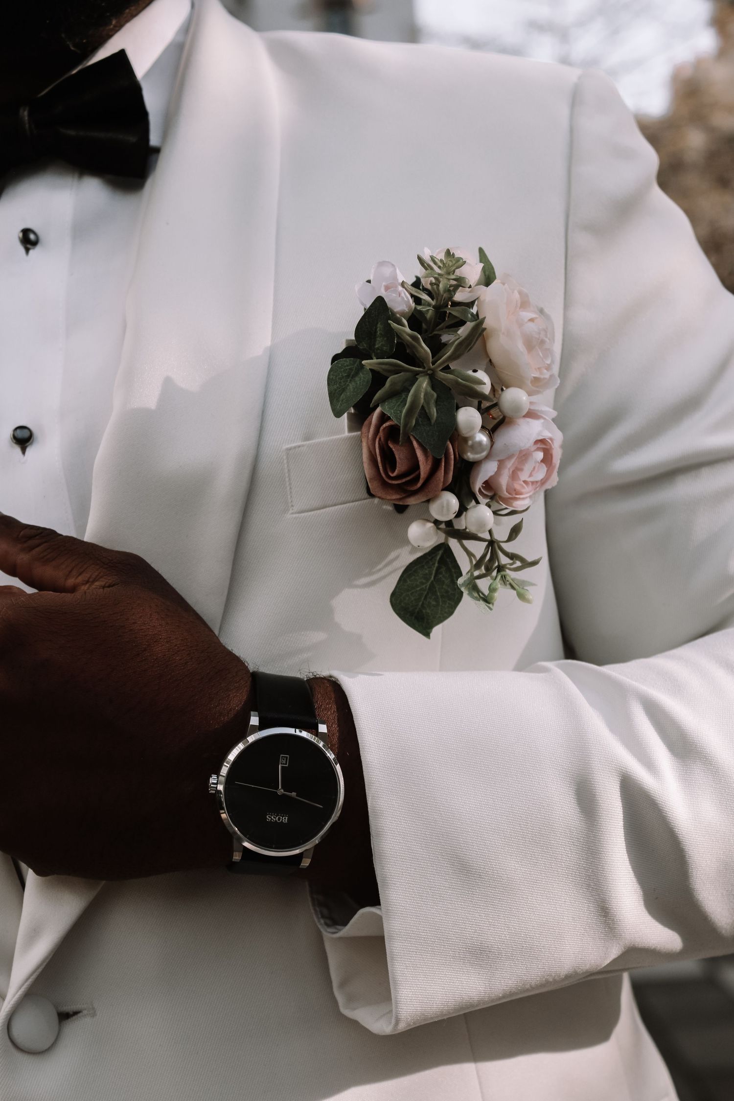 Close-up of boutonniere and fashion details on white tuxedo jacket.
