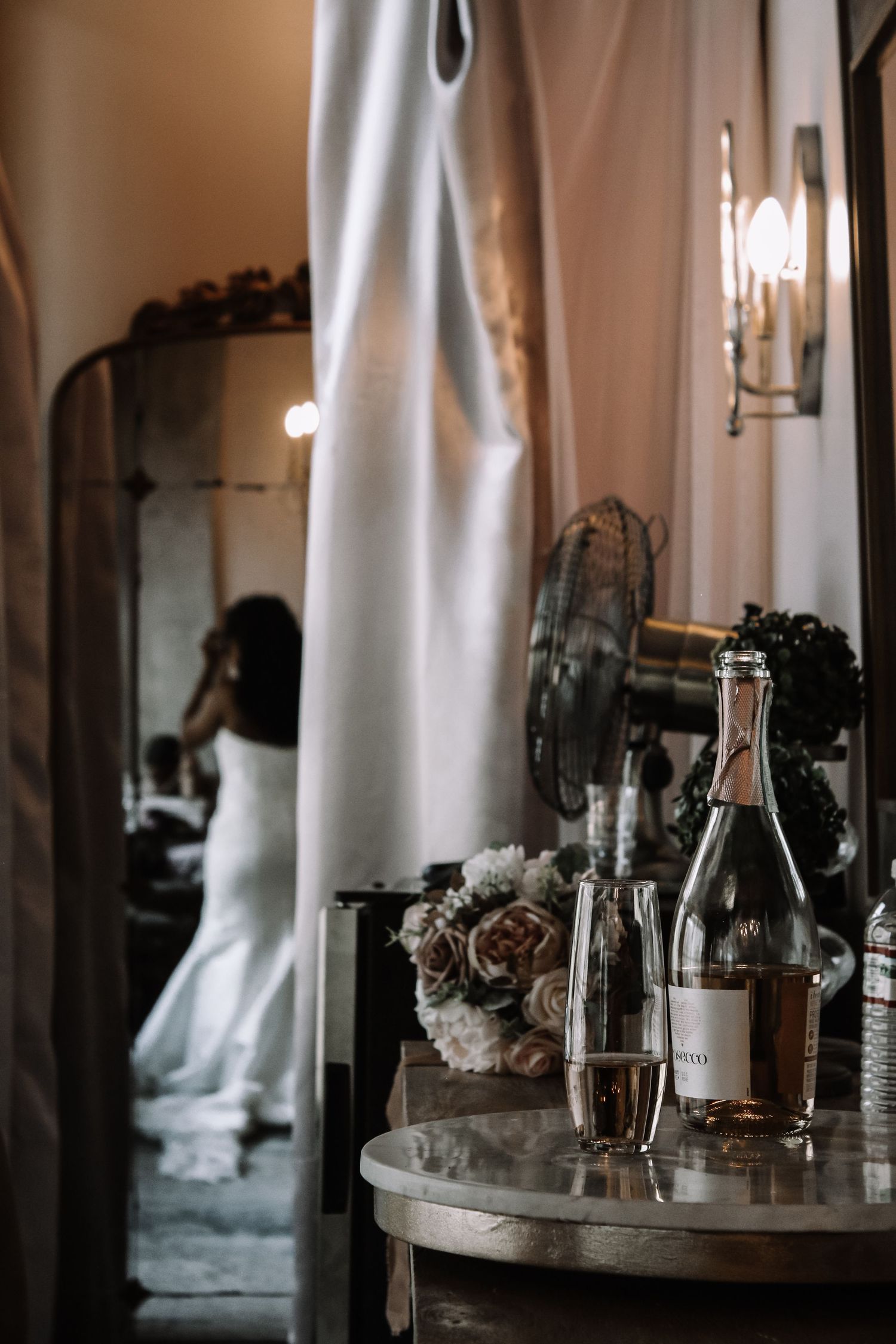 Elegant wedding reception details with candles and floral arrangements on mirrored table.